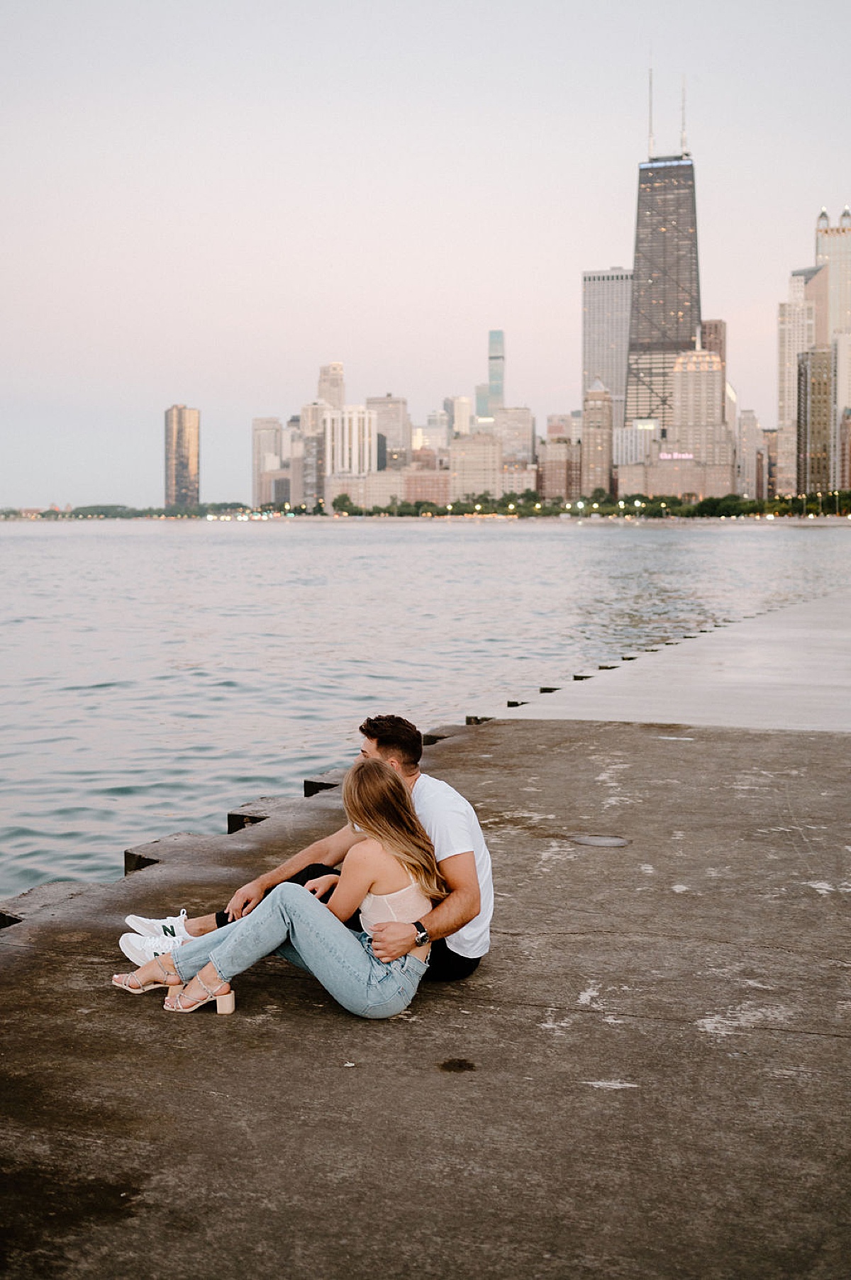 man and woman sit by the water during hip chicago engagement shoot by Indigo Lace Collective