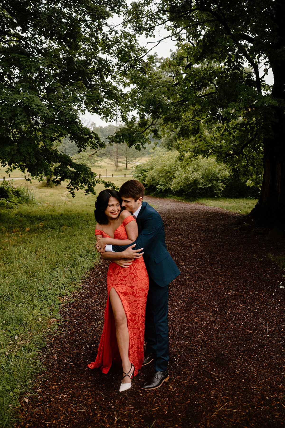 man and woman embrace wearing elegant evening dress in outdoor mortem arboretum engagement session