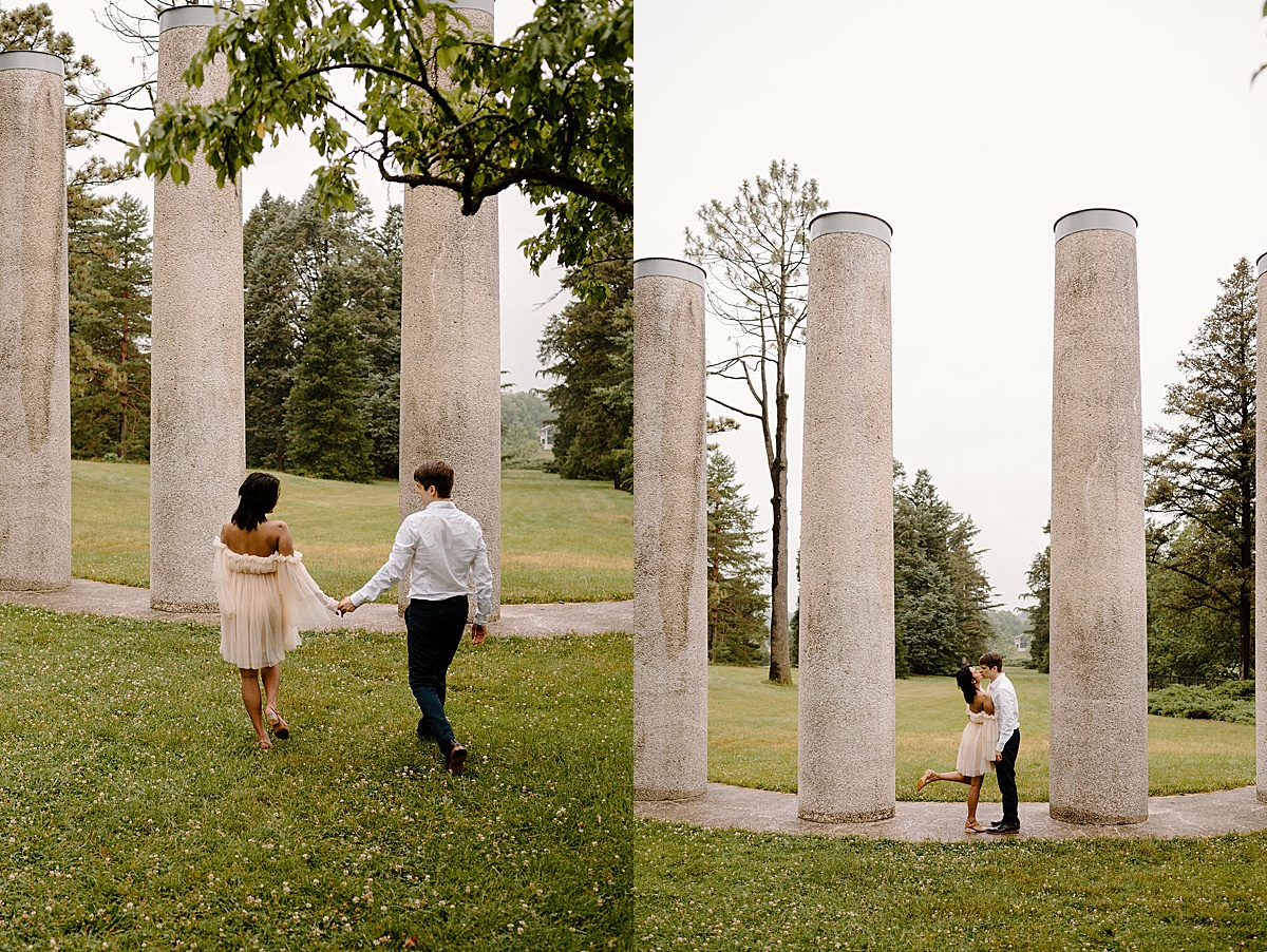 man and woman walk between romantic columns during engagement shoot by midwest wedding photographer