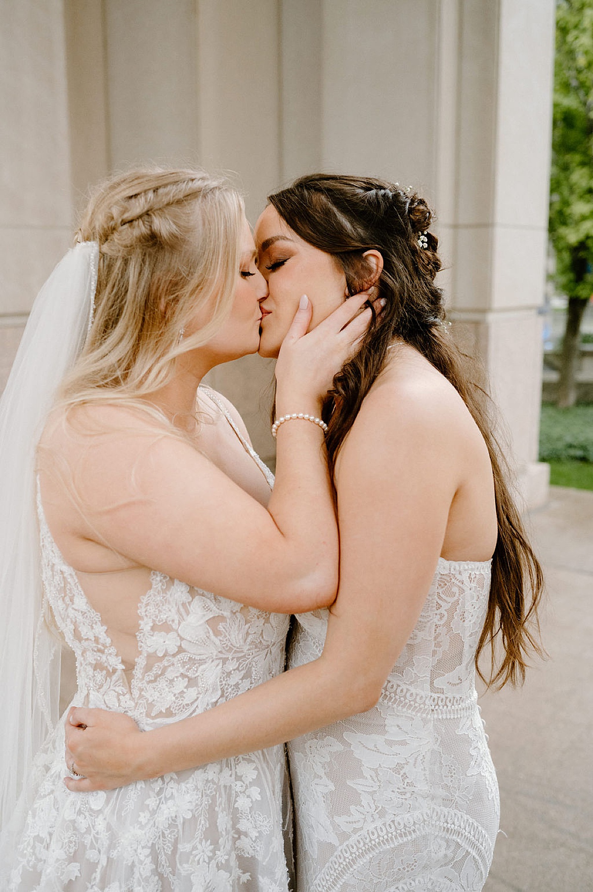 Two women in bridal gowns kiss before getting married in ceremony shot by midwest wedding photographer