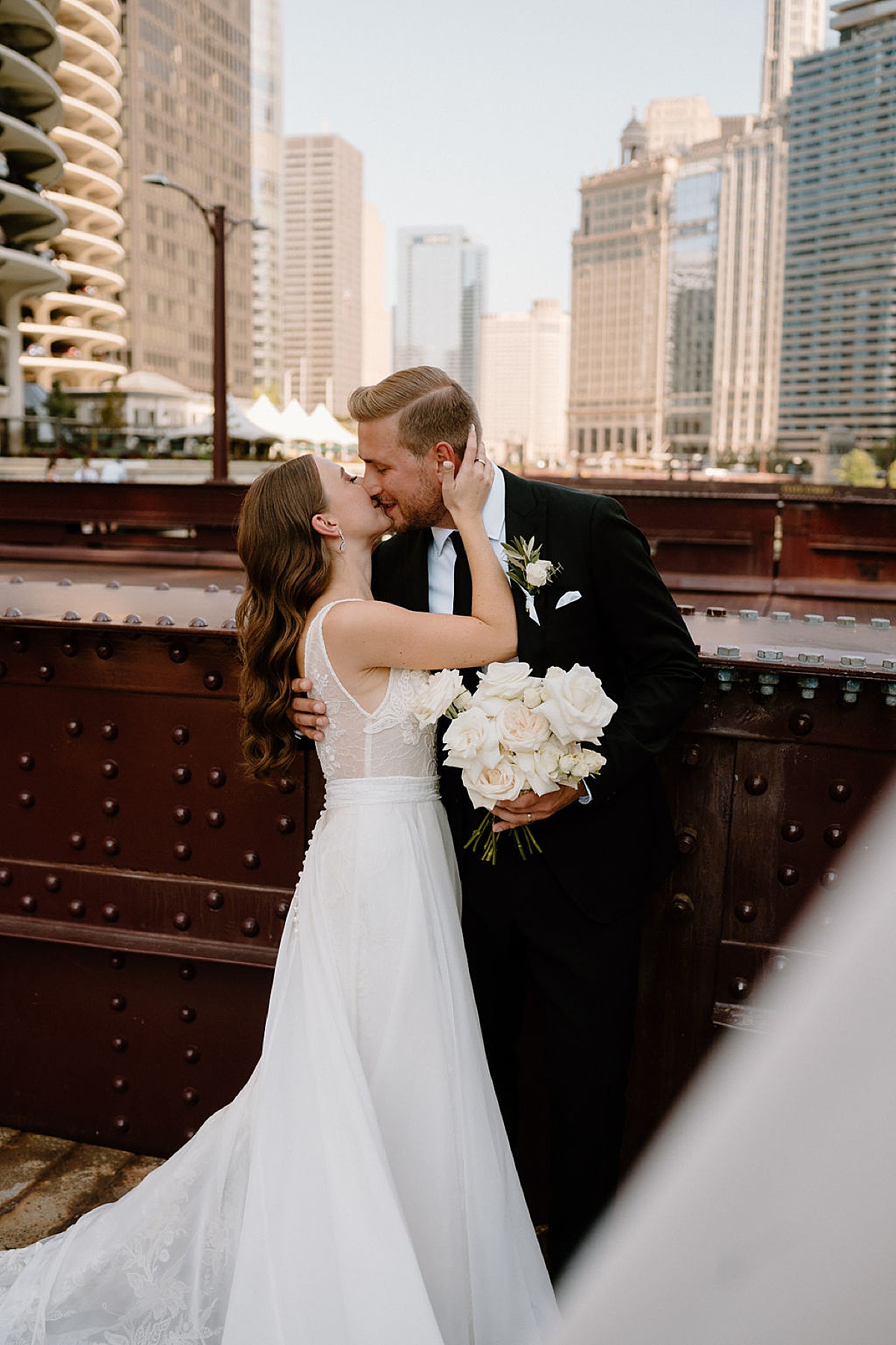 bride and groom pose on iron bridge over Chicago river during elegant editorial wedding at bridgeport art center