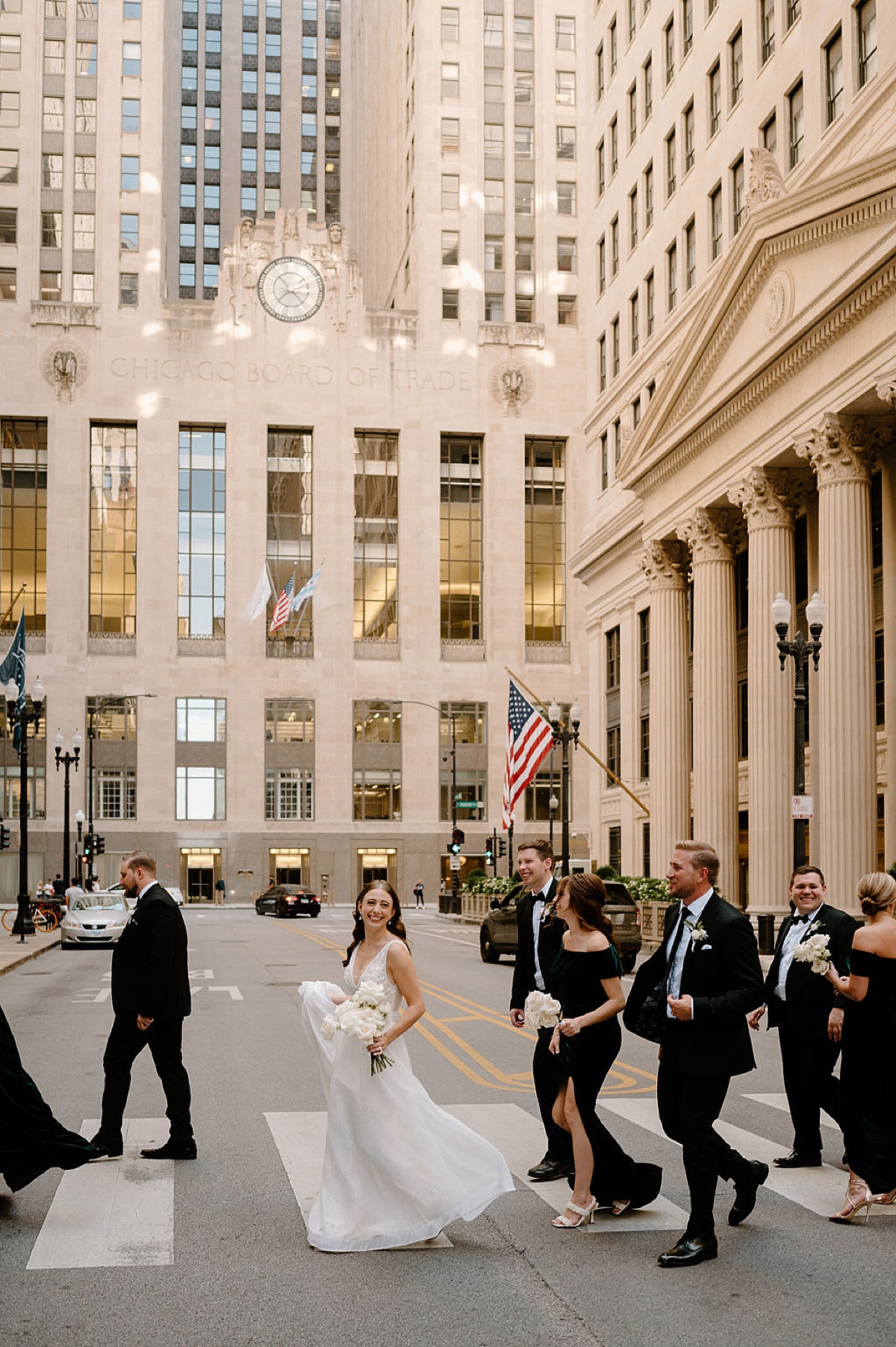 wedding party dressed in black and white walks across busy chicago street during shoot by Indigo Lace Collective