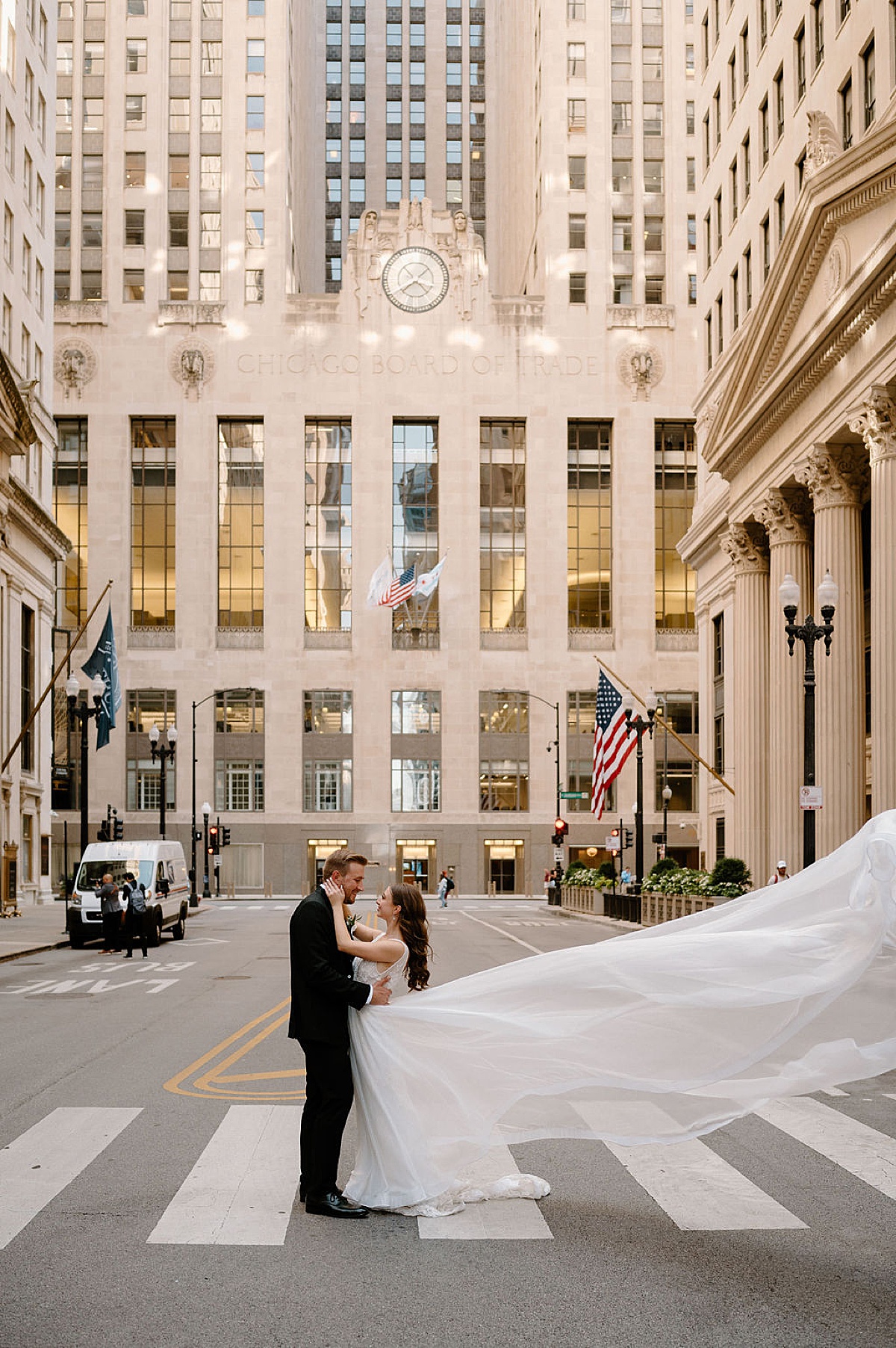 Bride and groom pose in chicago street with amazing gown train flowing in the wind during shoot by Indigo Lace Collective