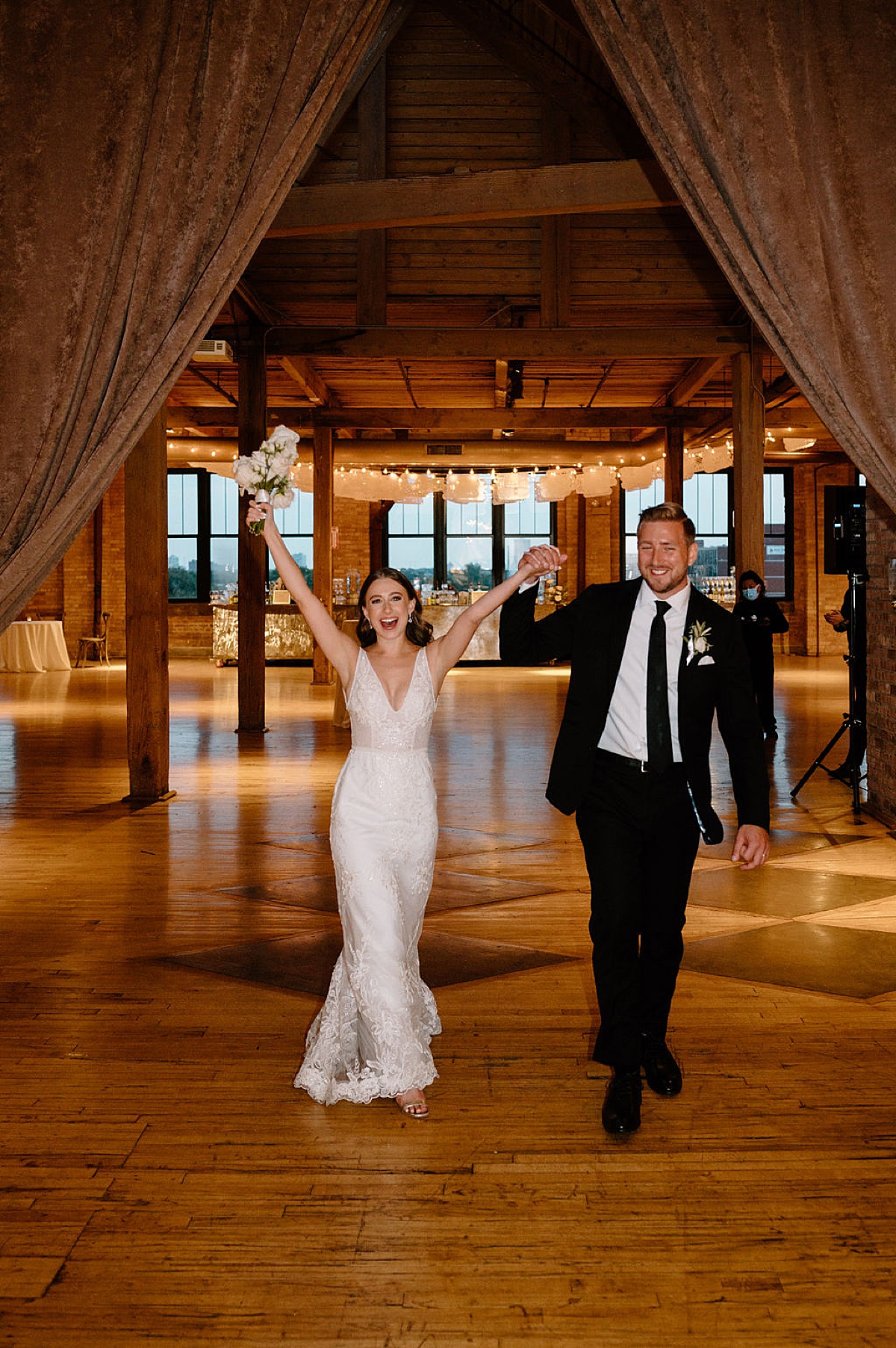bride and groom joyfully enter reception in loft venue shot by midwest wedding photographer