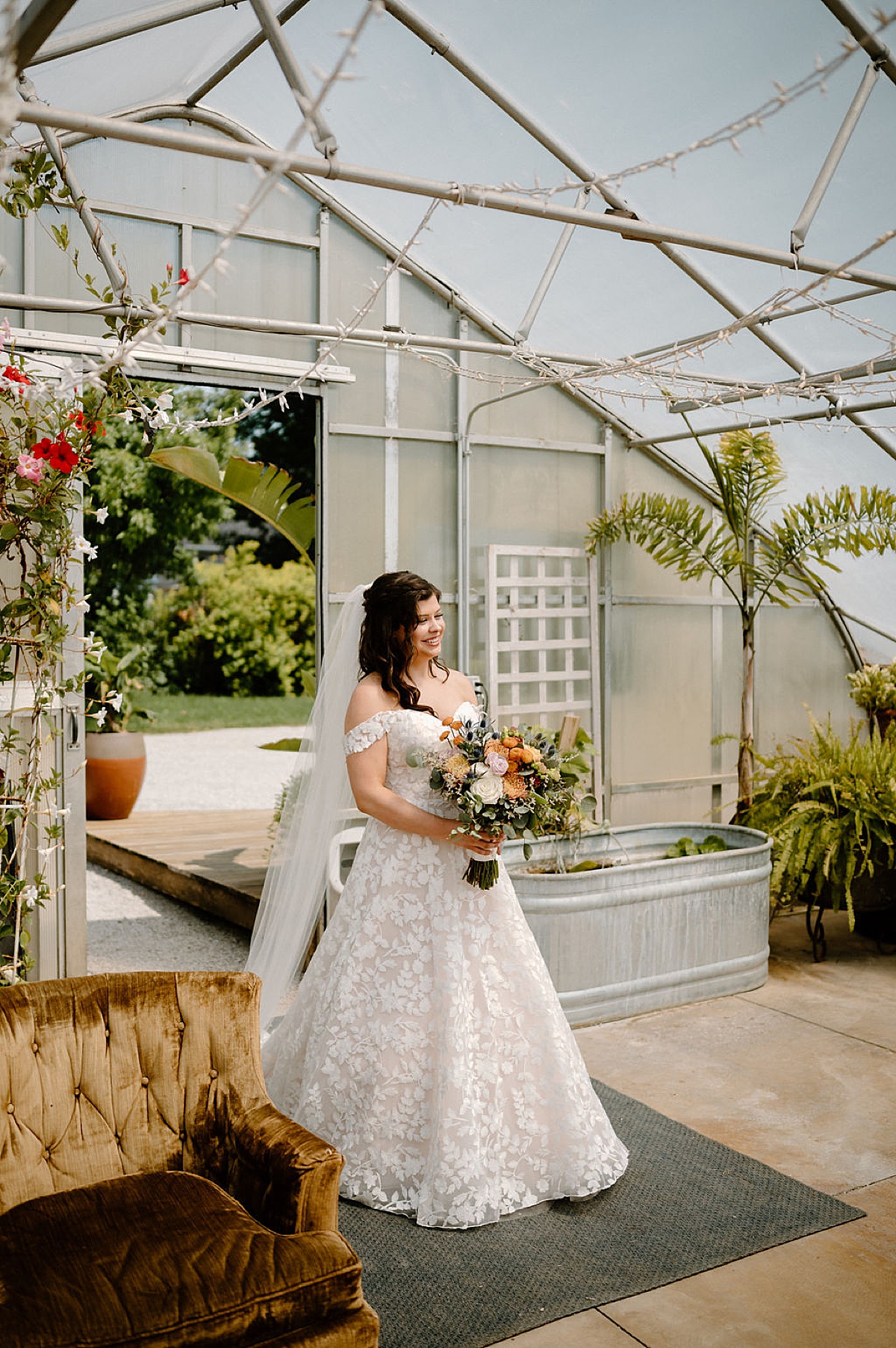 bride in leaf embellished gown and boho bouquet enters greenhouse for first look at rustic summer wedding at Heritage Prairie Farm