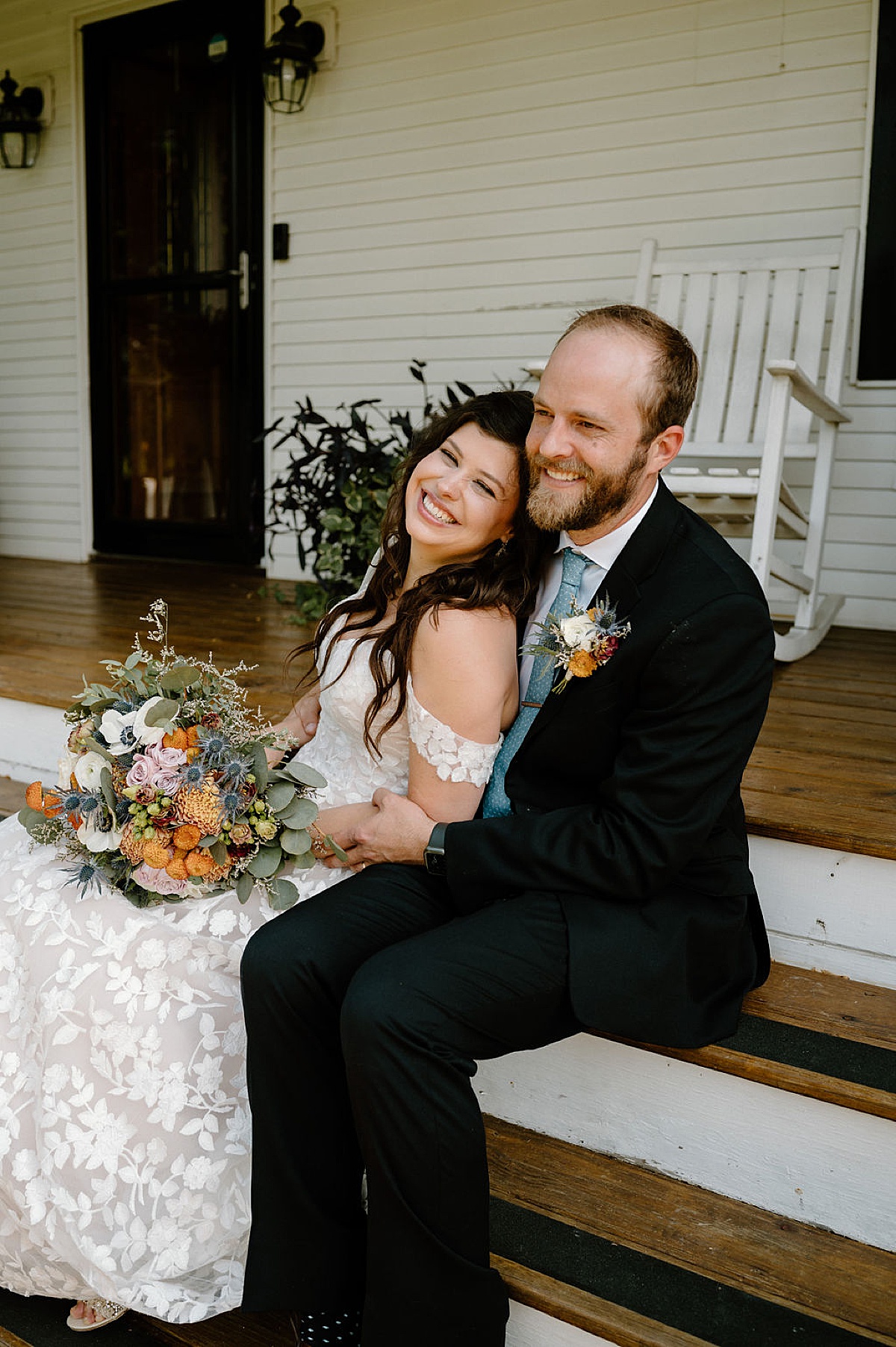 boho rustic bride and groom pose on farmhouse porch after ceremony shot by indigo lace collective