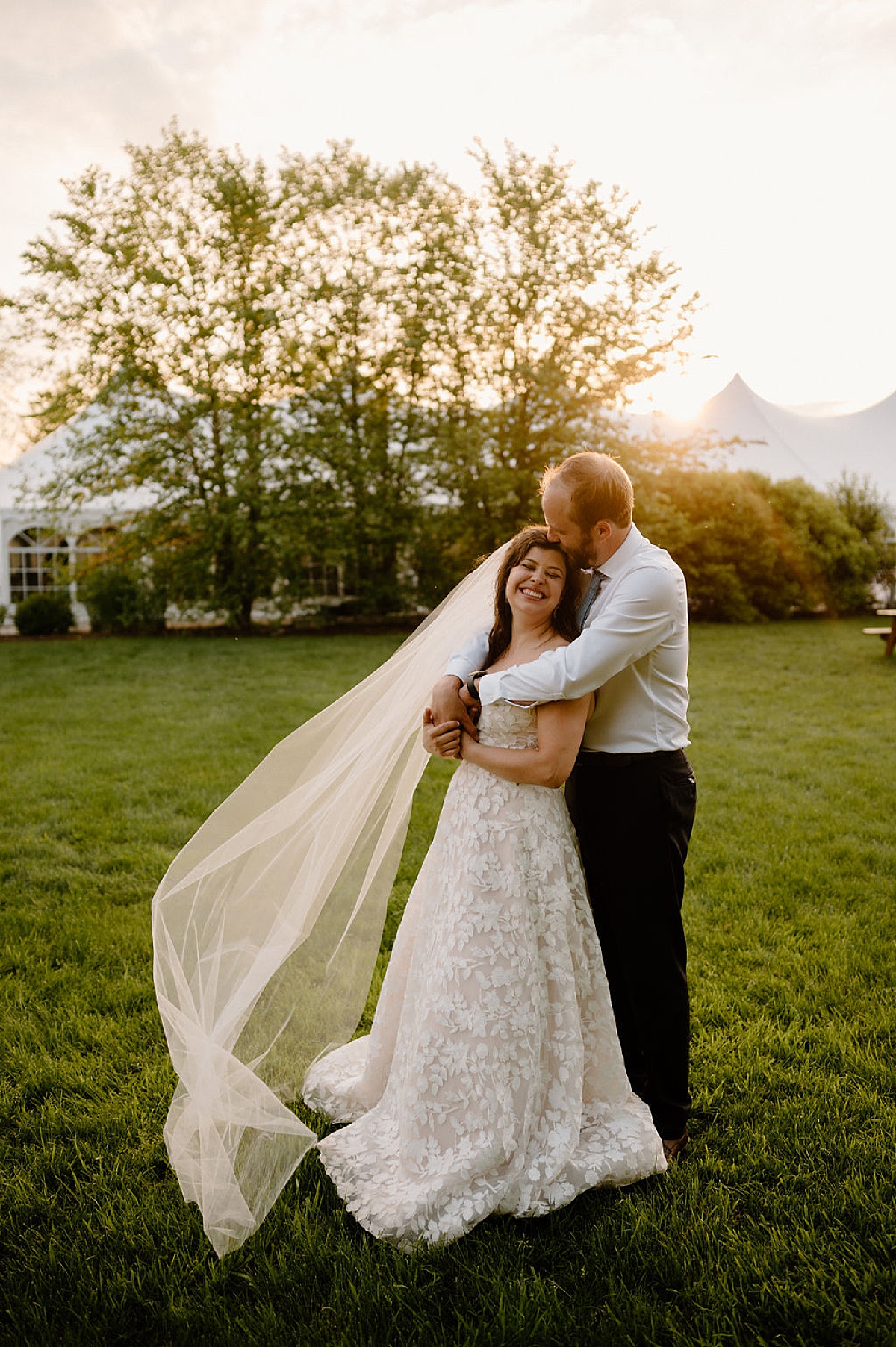 groom kisses bride's forehead during golden hour on venue lawn after ceremony shot by midwest wedding photographer