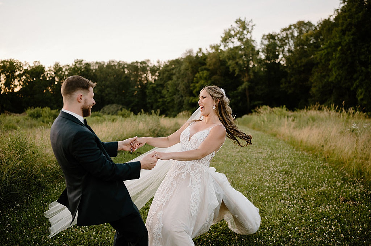 bride and groom twirl in a field of clover during good vibes summer wedding at union 12