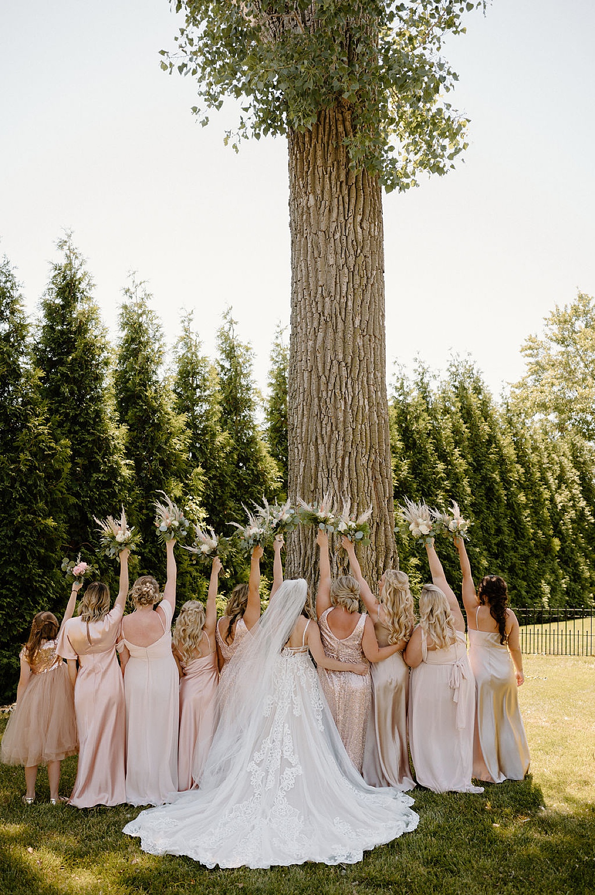 bridesmaids in pastel satin and sequin gowns raise boho bouquets in the air during good vibes summer wedding at union 12