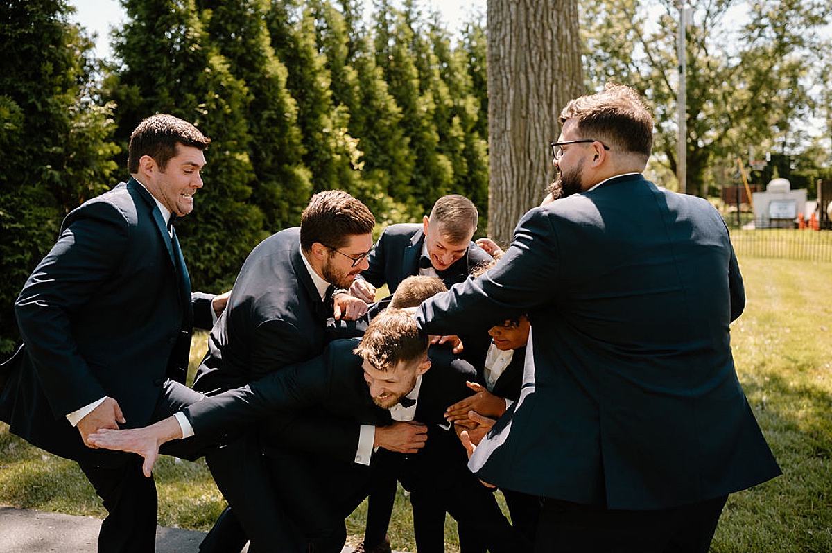 groomsmen tussle with the groom during pre-ceremony portraits by midwest wedding photographer