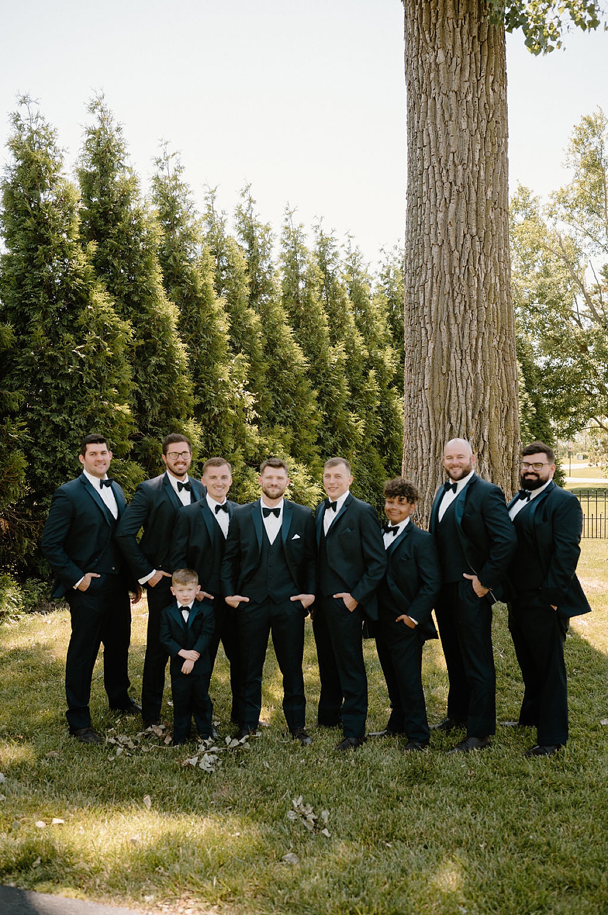 groomsmen pose in tuxes with groom before ceremony shot by midwest wedding photographer