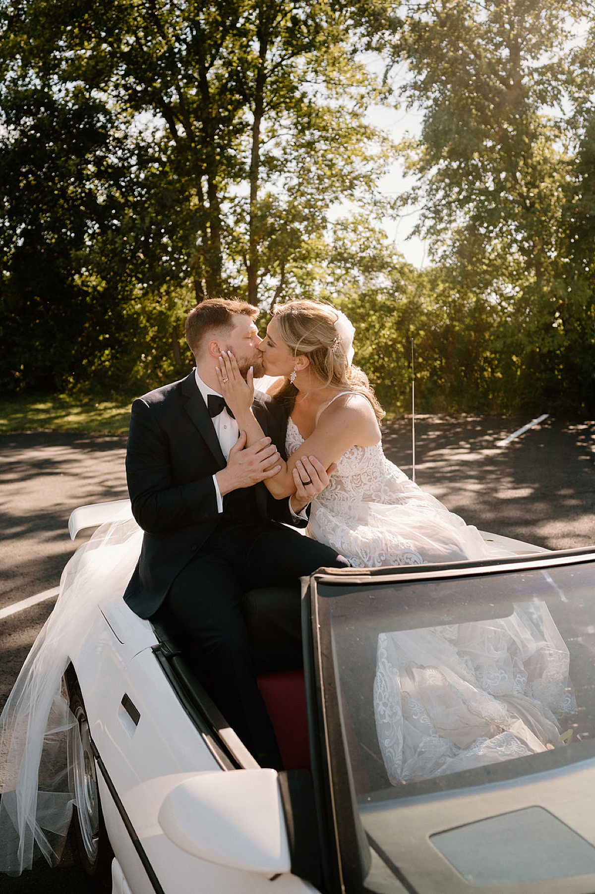 newlywed bride and groom kiss in the back of a white convertible after boho wedding shot by indigo lace collective