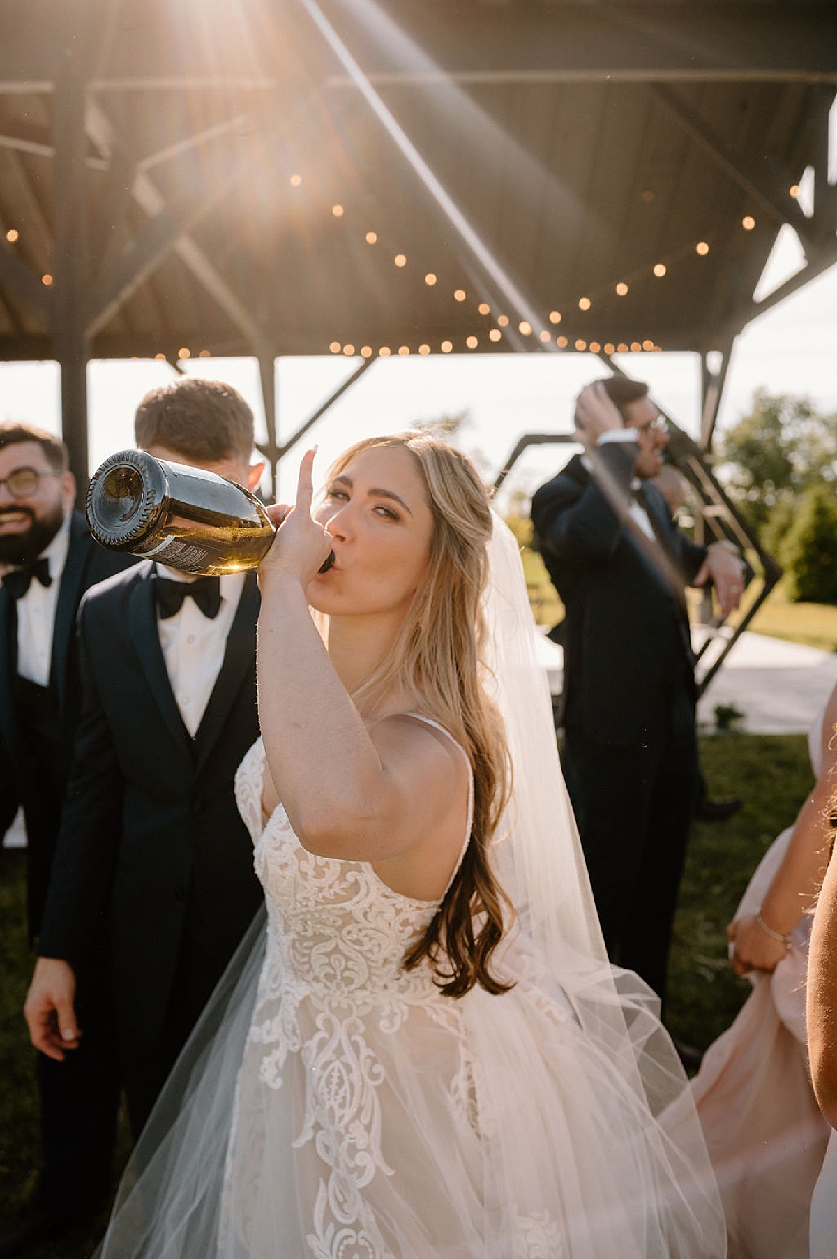 bride drinks from champagne bottle after boho summer wedding shot by indigo lace collective in fort wayne