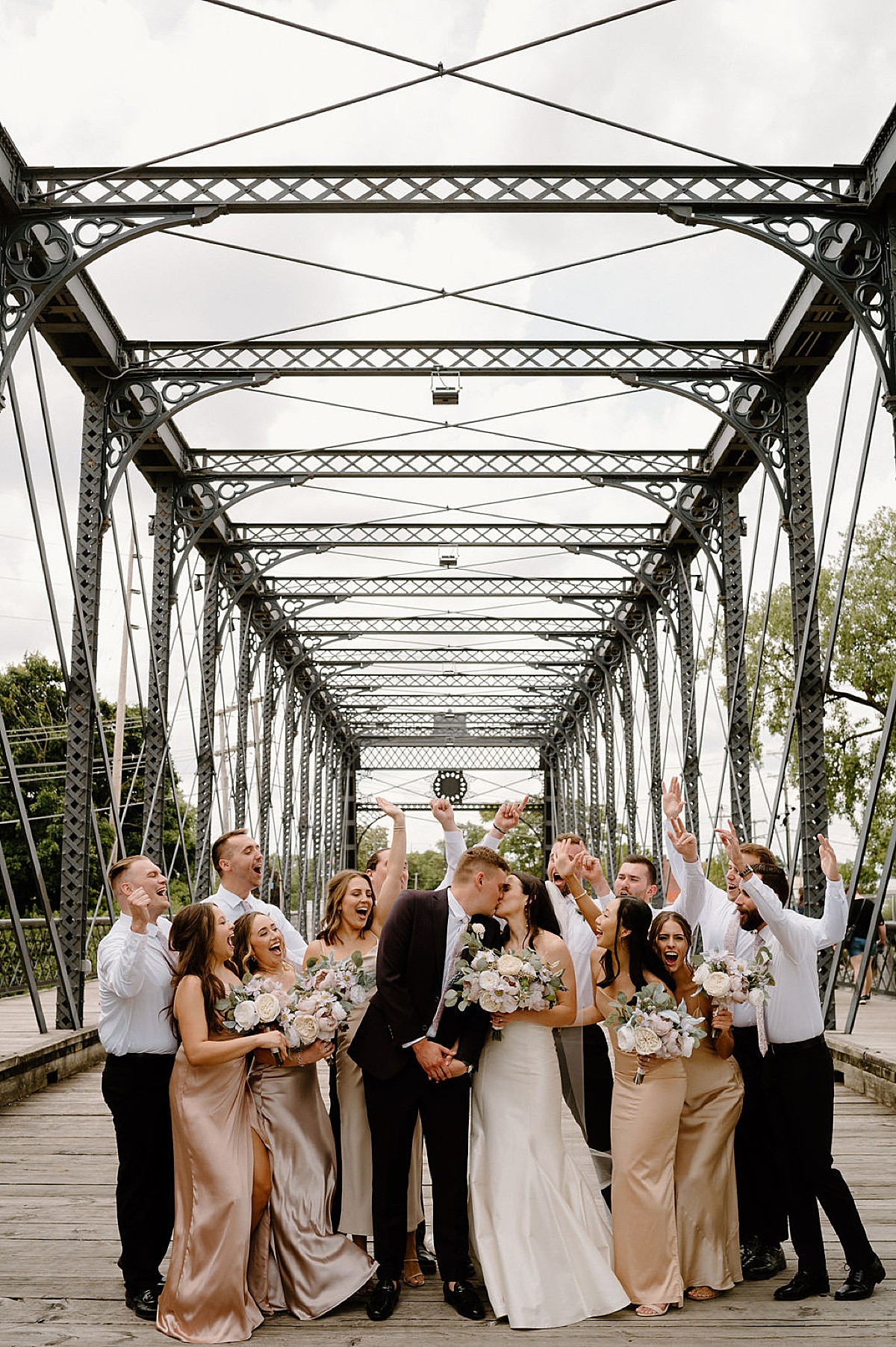 wedding party cheers as bride and groom kiss after elegant midwest wedding shot by Indigo Lace Collective