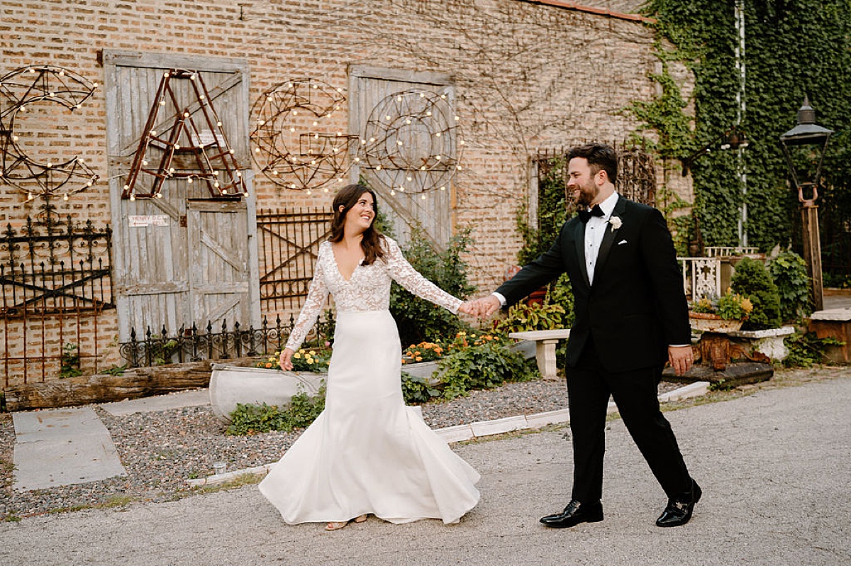 bride and groom walk hand in hand to reception at salvage one summer wedding