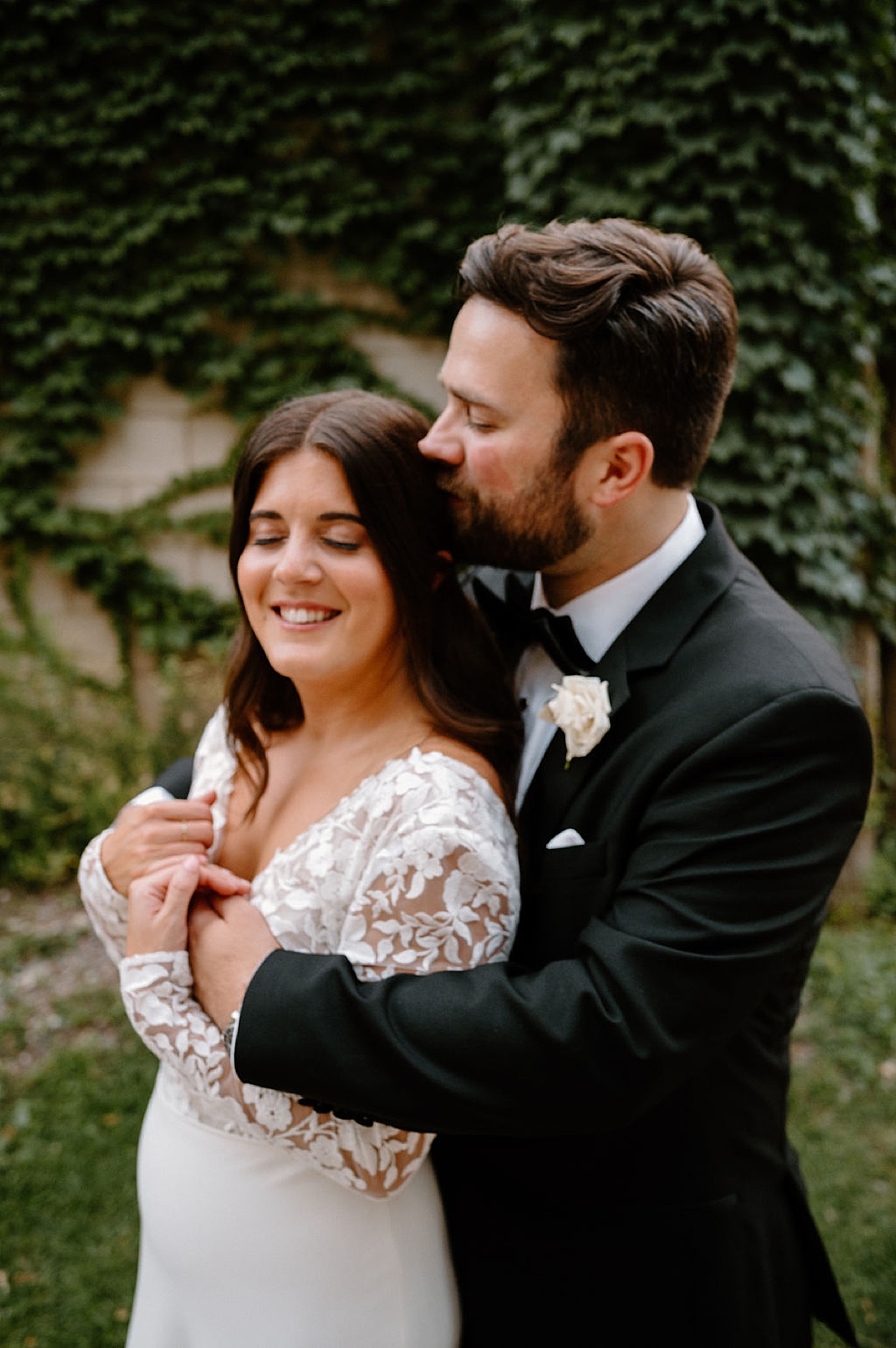 groom kisses bride in front of ivy wall after elegant boho ceremony shot by Indigo Lace Collective