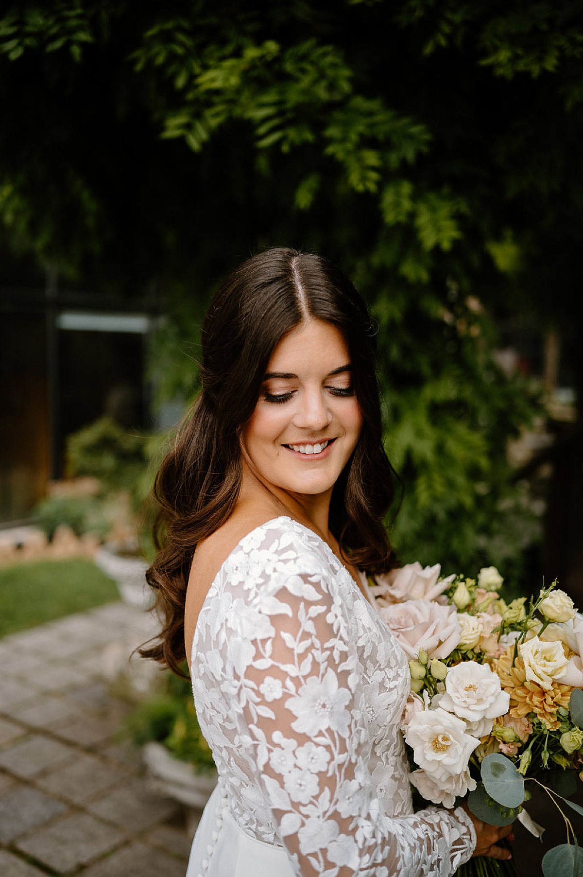 bride poses in applique lace gown with pale pink and gold roses bouquet shot by chicago wedding photographer