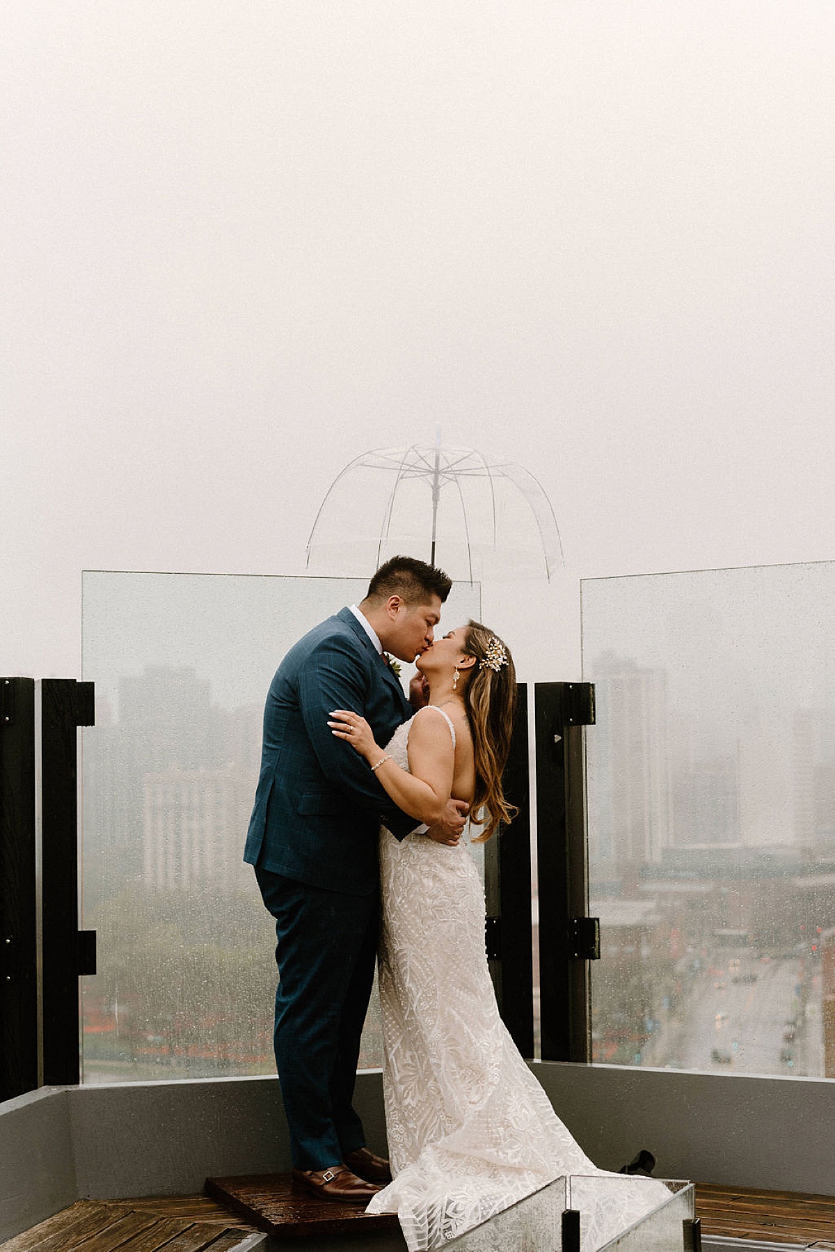 newlywed couple kiss on a rooftop in the rain during Ravenswood event center spring wedding