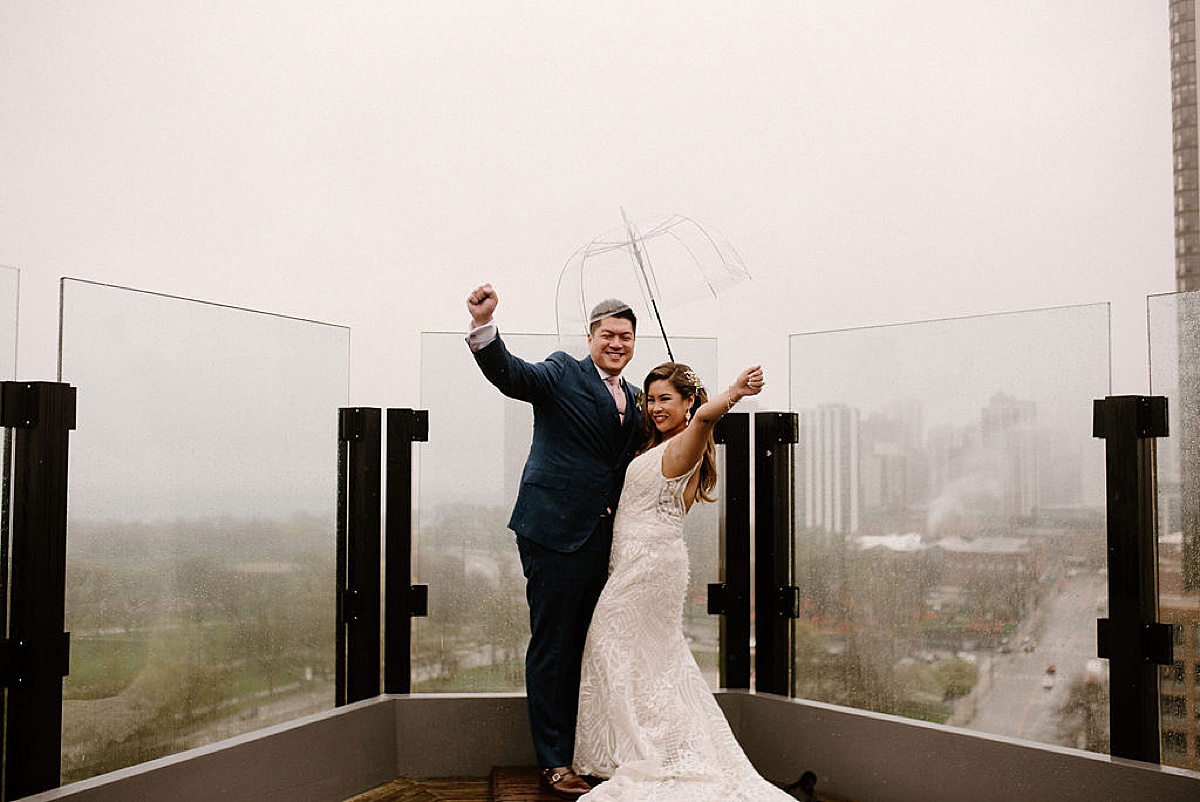 bride and groom celebrate on a rainy rooftop during Ravenswood event center spring wedding