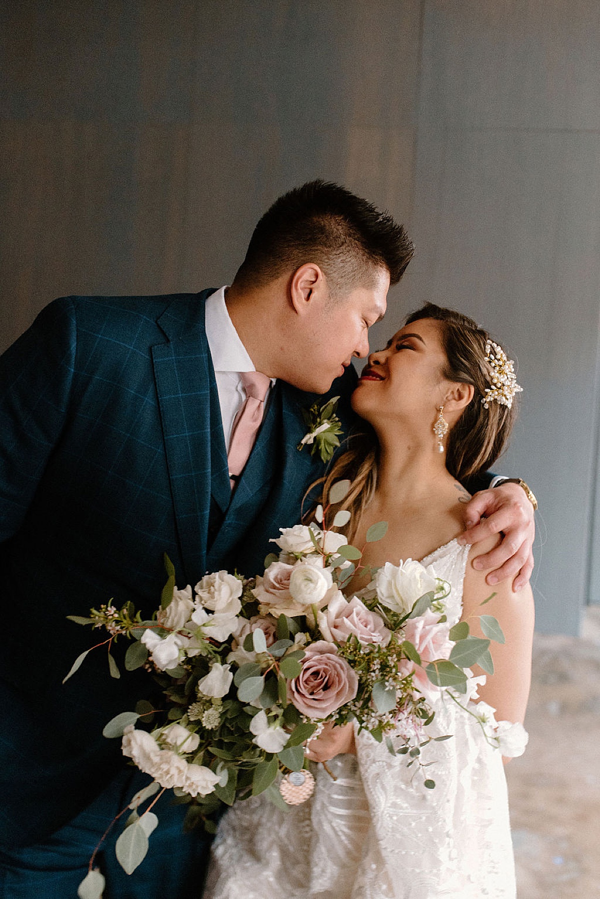groom in navy blue tux, and bride with elegant hairpiece and pastel bouquet share a moment captured by chicago wedding photographer