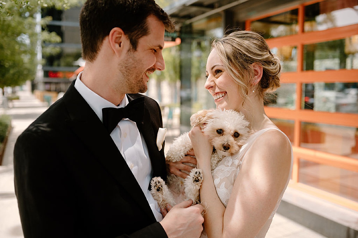 bride and groom cuddle their cute puppy before romantic Sami and Andrew's Salvage One Summer Wedding