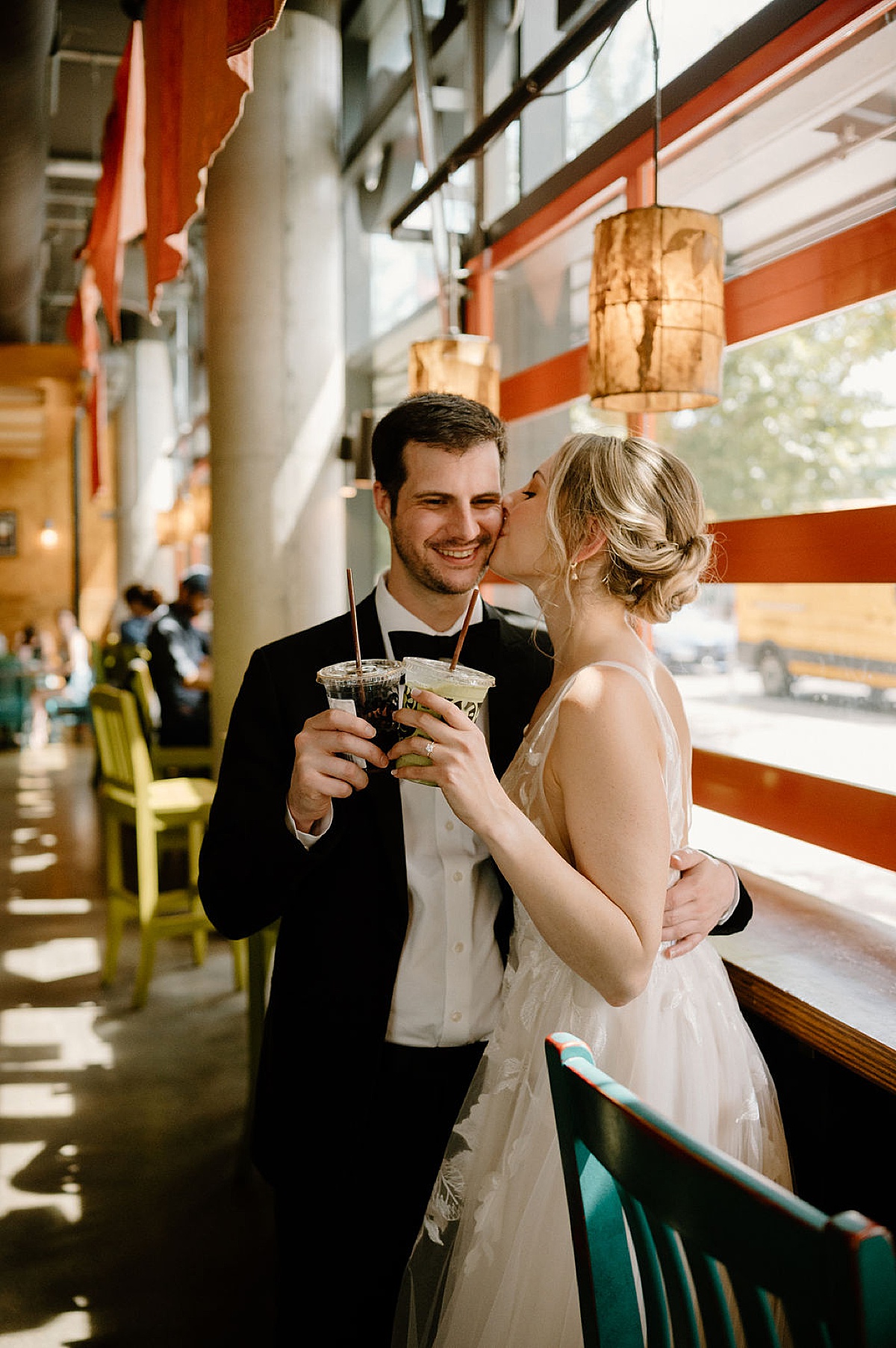 bride and groom share a kiss while at cafe getting drinks before ceremony shot by chicago wedding photographer