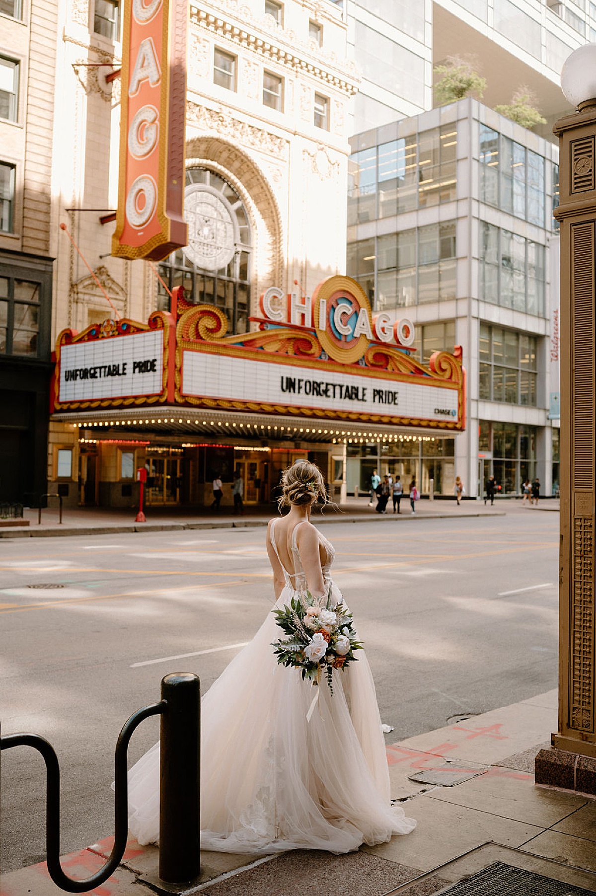 bride in boho tulle wedding gown holds bouquet and poses on vintage chicao street | Indigo Lace Collective