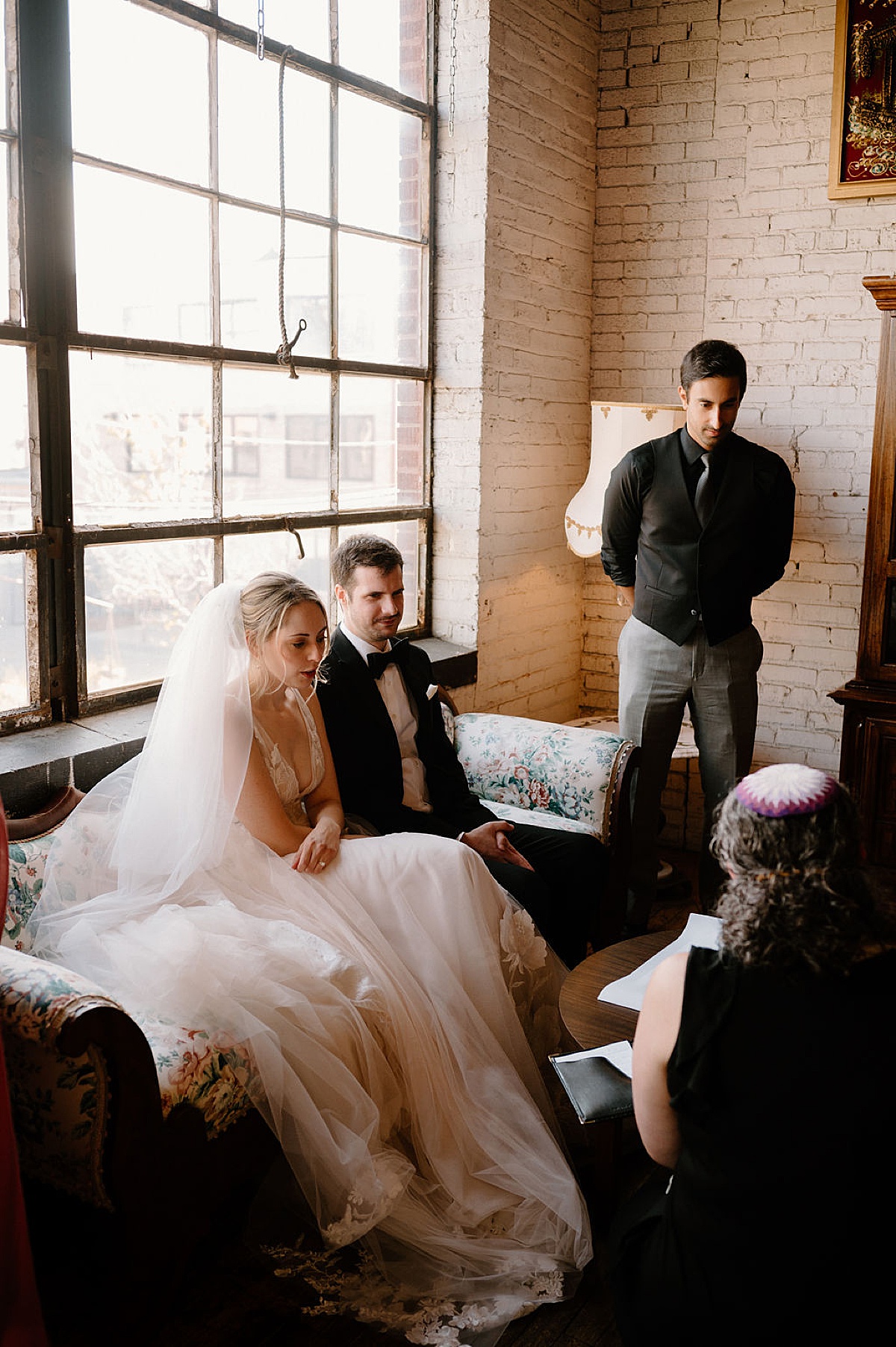 bride in romantic tulle gown and veil sits with groom as they sign the marriage license before ceremony shot by Indigo Lace Collective