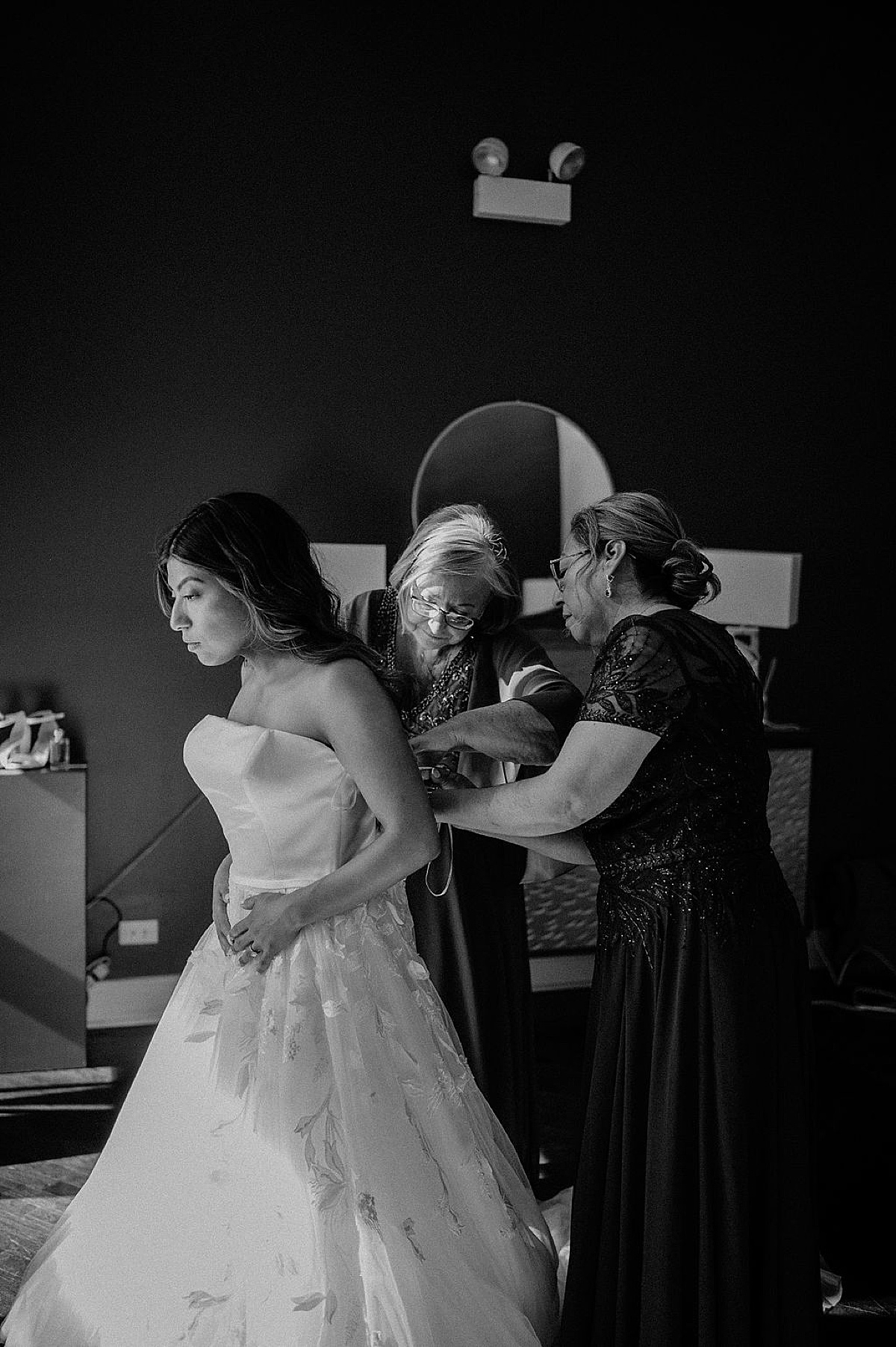 mother and grandmother of the bride help her lace up gown before Mae District intimate Chicago Wedding