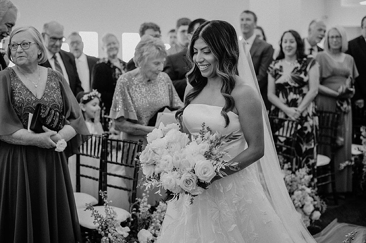 bride with white roses and veil walks down the aisle at Mae District intimate Chicago Wedding