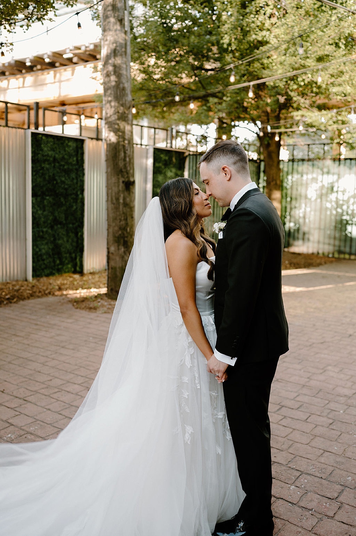 bride in tulle and satin gown poses with groom outdoors shot by Chicago wedding photographer