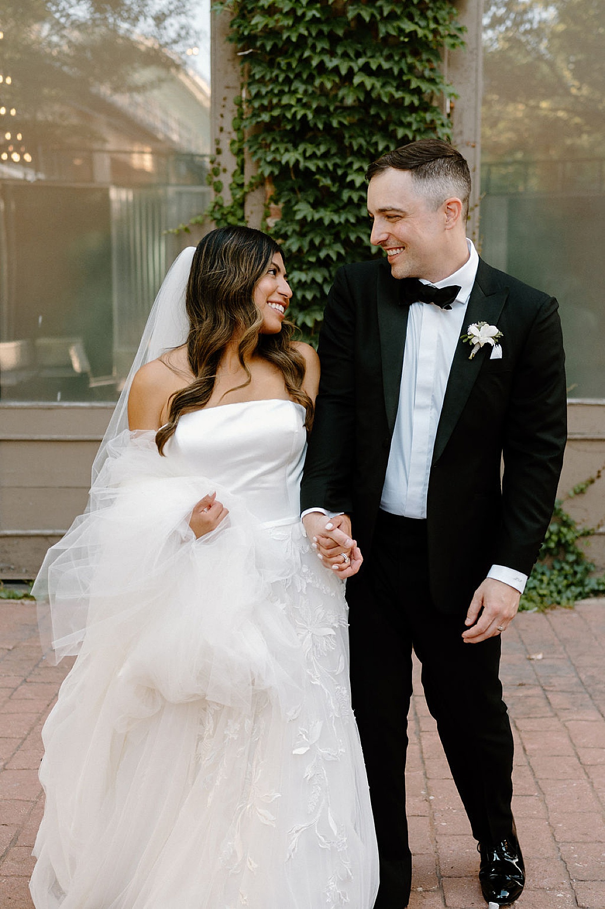classy bride in tulle and satin gown holds groom's hand photographed by Chicago wedding photographer