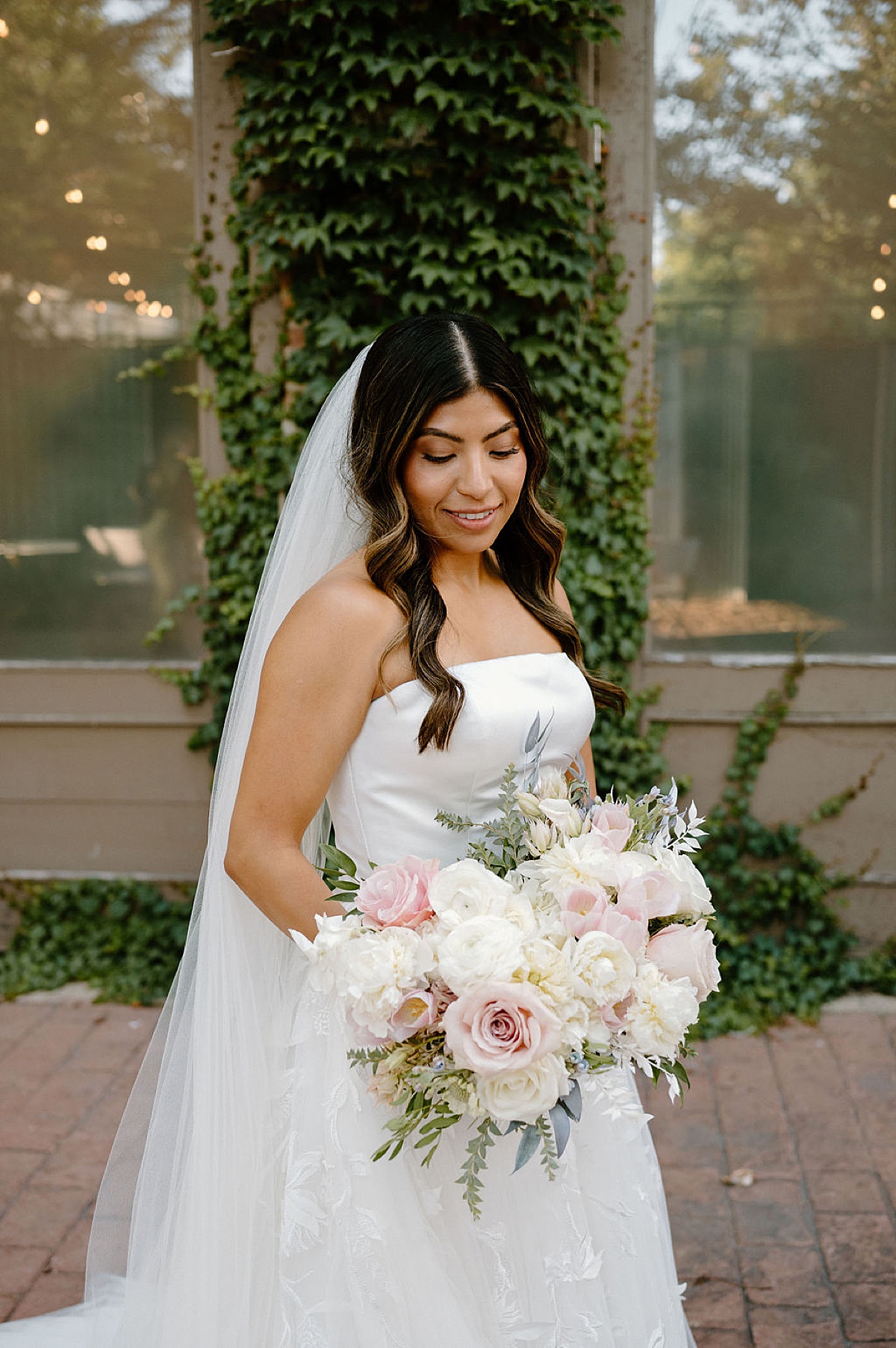 bride in romantic gown with pale pink and white rose bouquet poses for Chicago wedding photographer