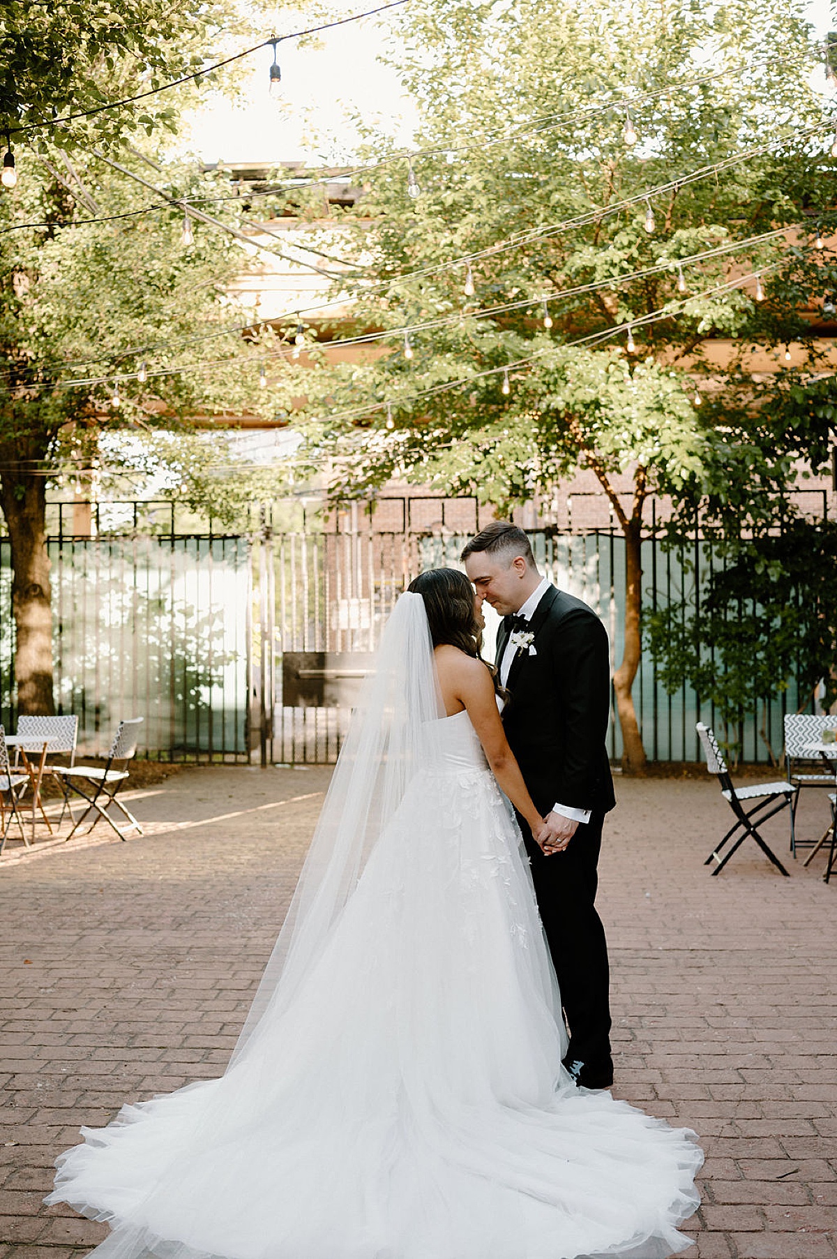 bride in long veil and tulle gown poses with groom in tux after wedding shot by Indigo Lace Collective