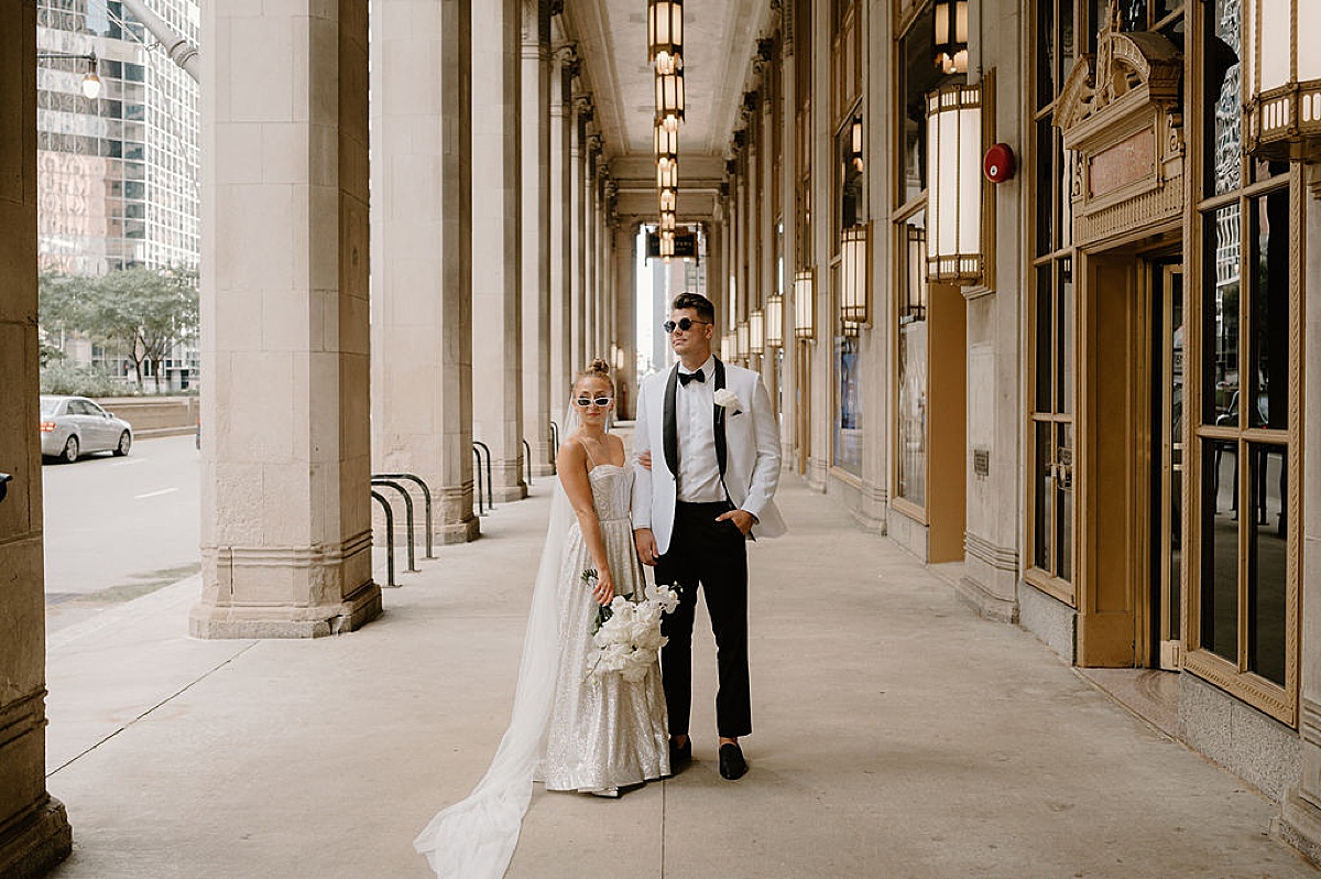 groom in white evening jacket and bride in sparkly gown pose in sunglasses during Glitz & Glam Chicago Wedding