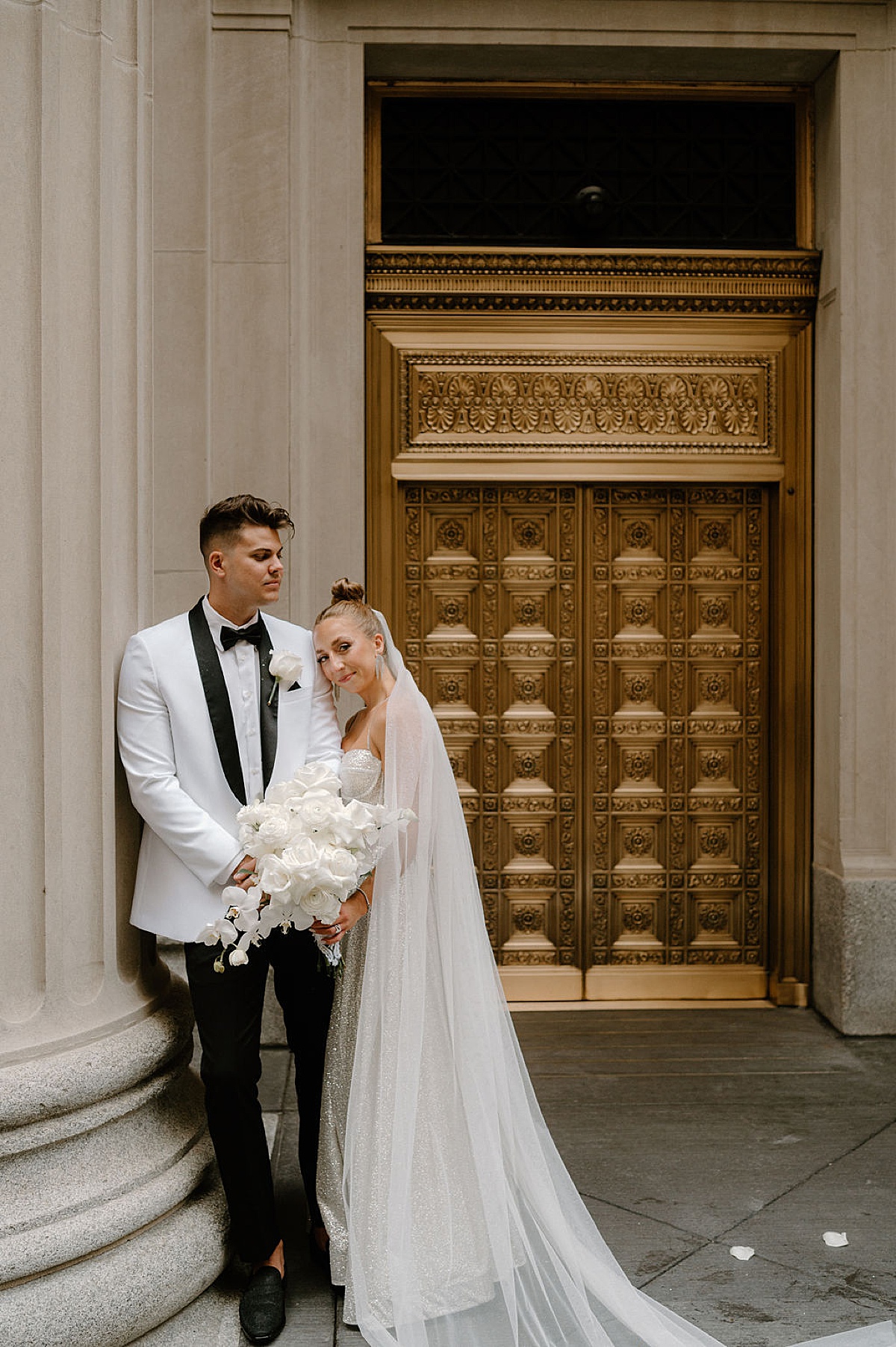 bride in silver sparkly gown poses with groom in white jacket holding white roses by Midwest wedding photographer 