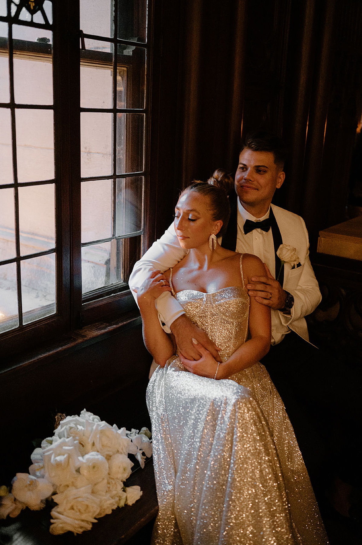 bride in silver glittery wedding gown with white rose bouquet poses with elegant groom for Indigo Lace Collective