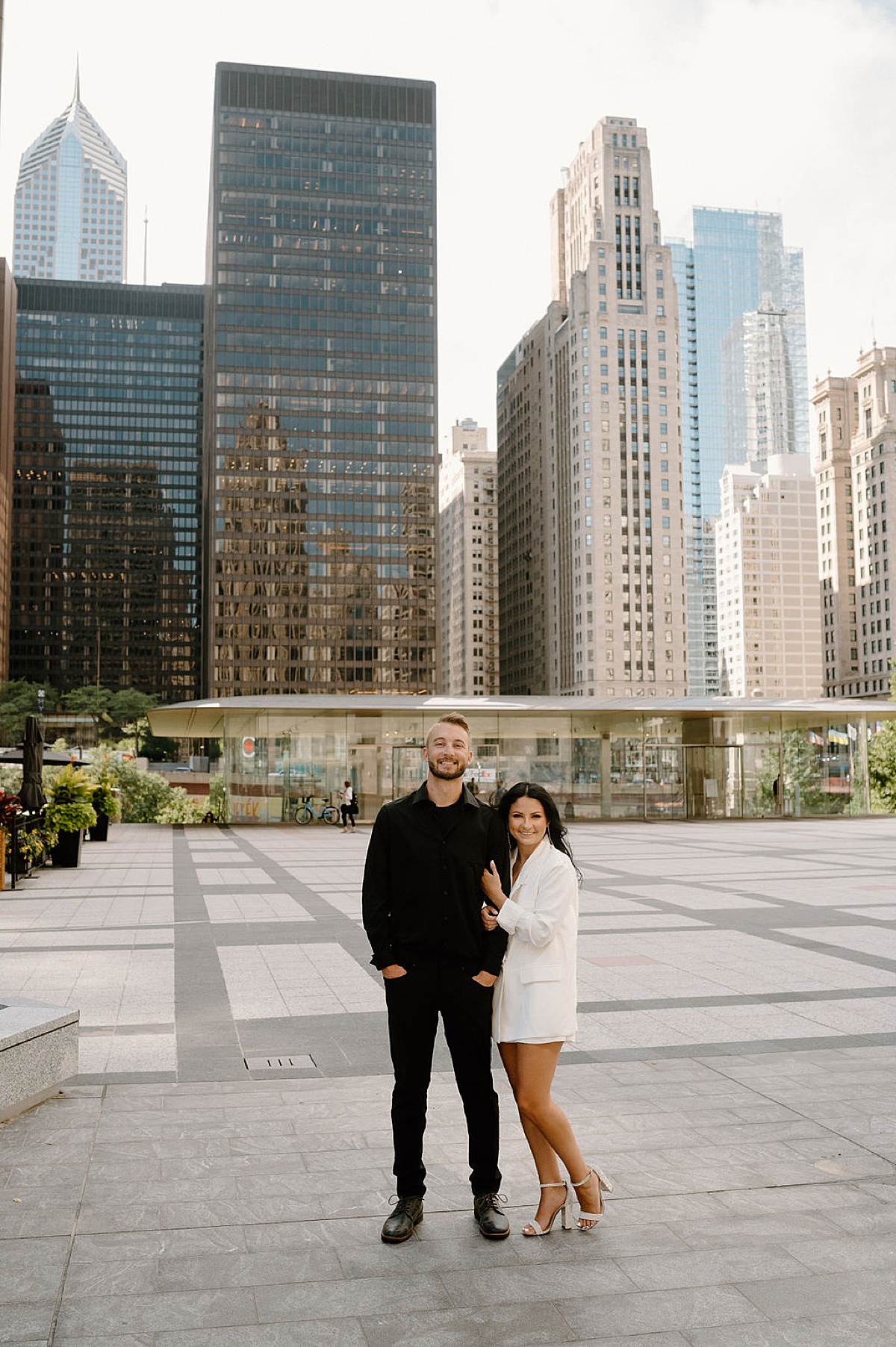 classy man and woman pose in city plaza during engagement shoot with Chicago wedding photographer