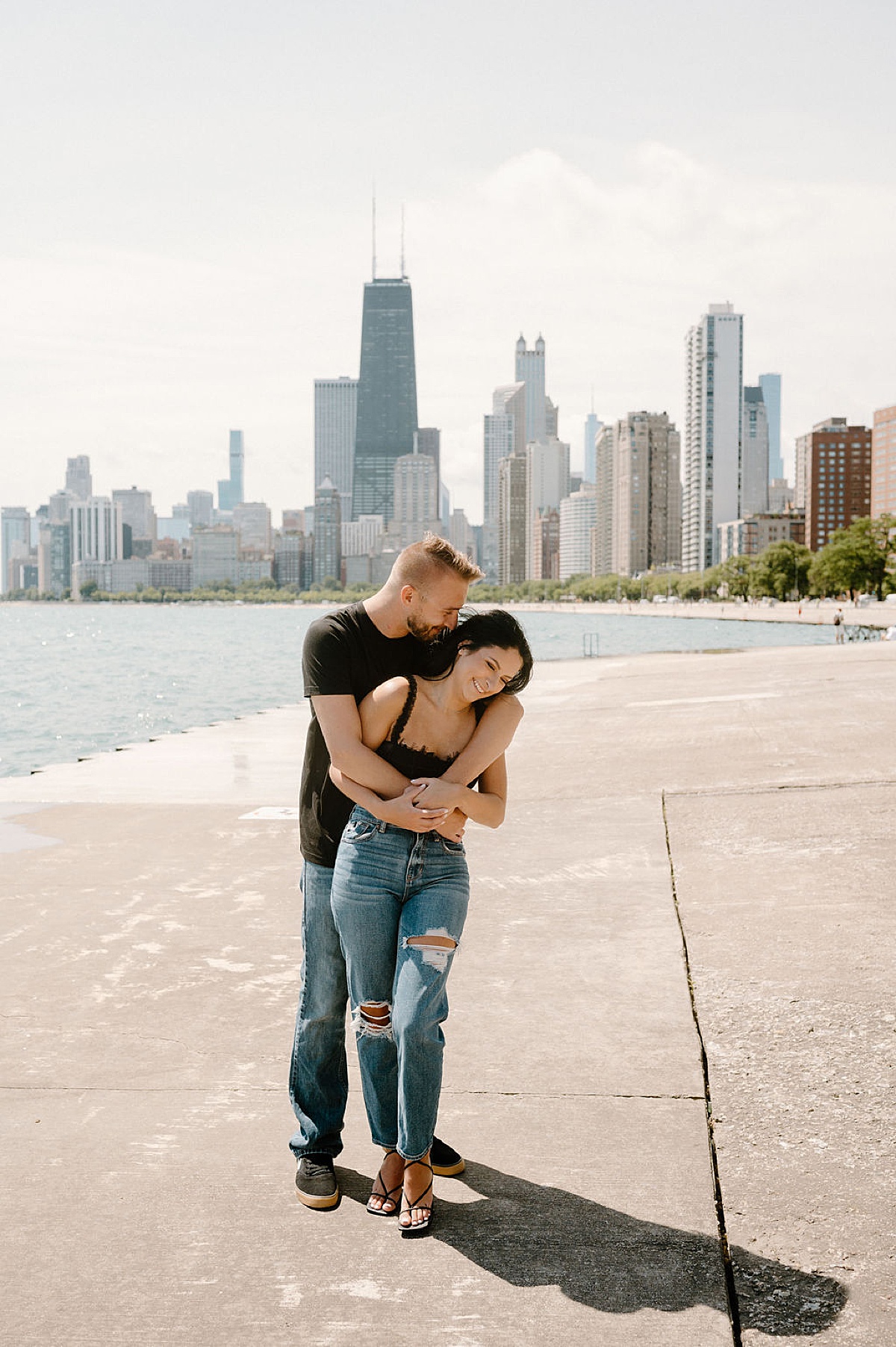 Young couple embrace in front of Chicago skyline during shoot with Indigo Lace Collective