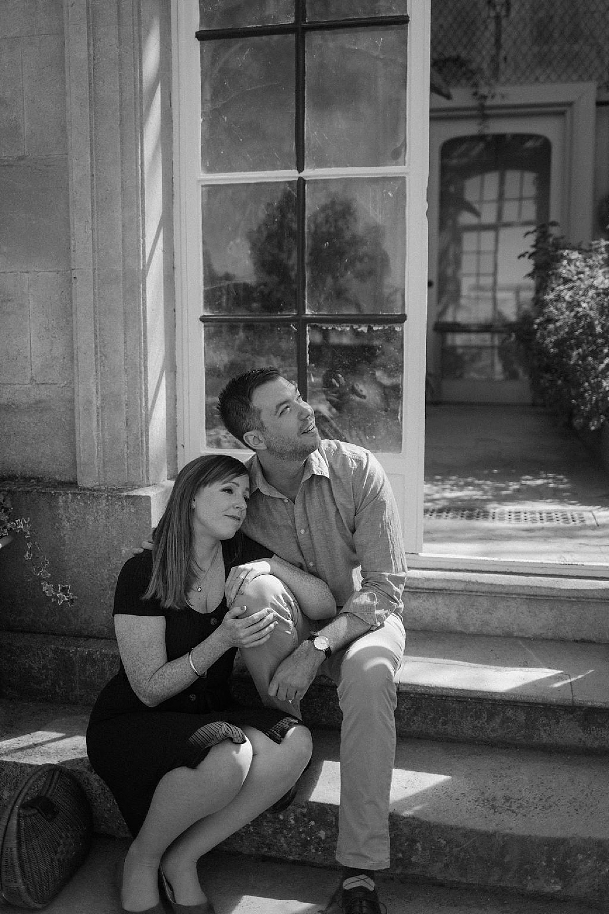Couple poses on greenhouse garden steps at old country home in England during Wrest Park Engagement session