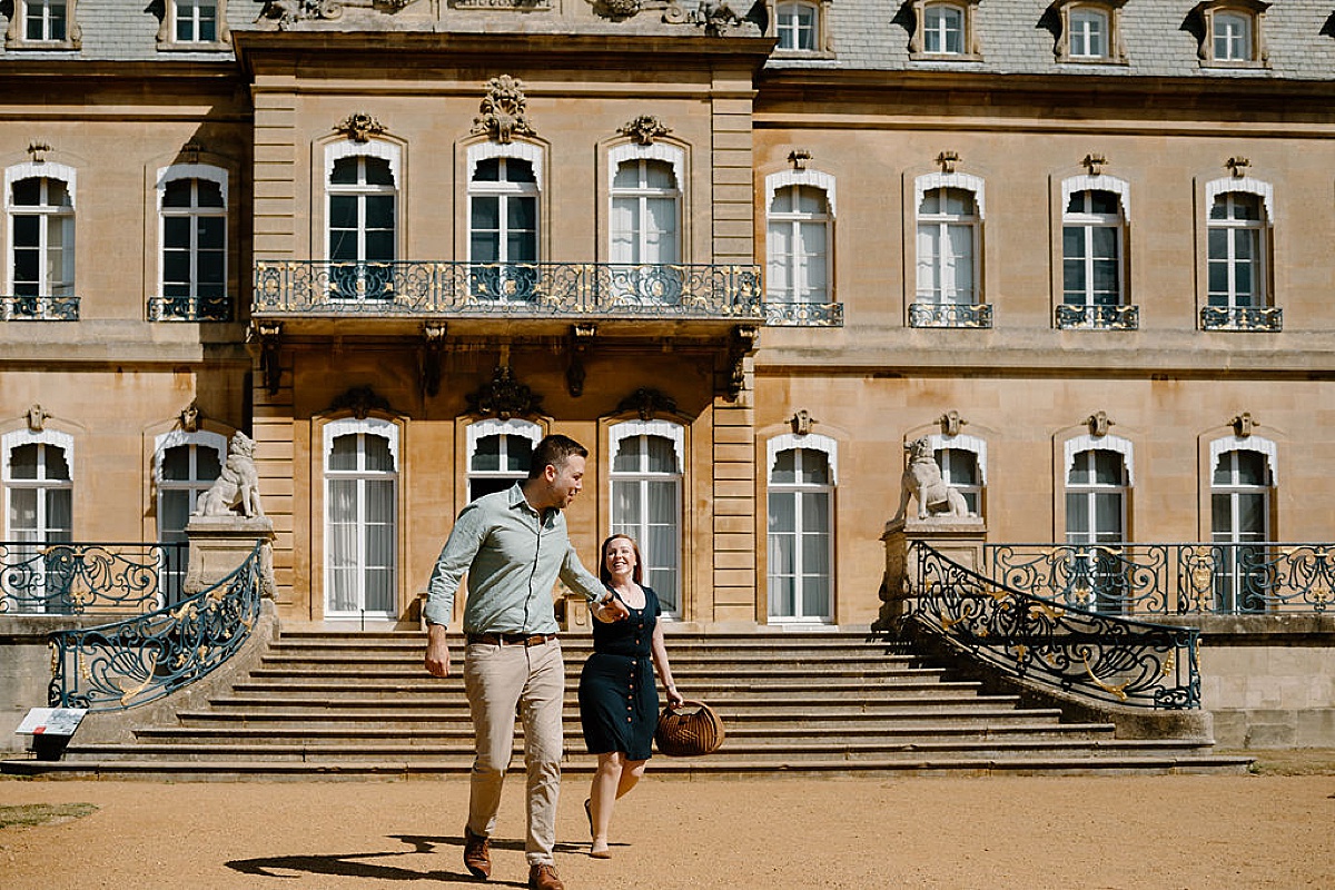 young couple runs down front steps of romantic country palace during engagement shoot by Indigo Lace Collective