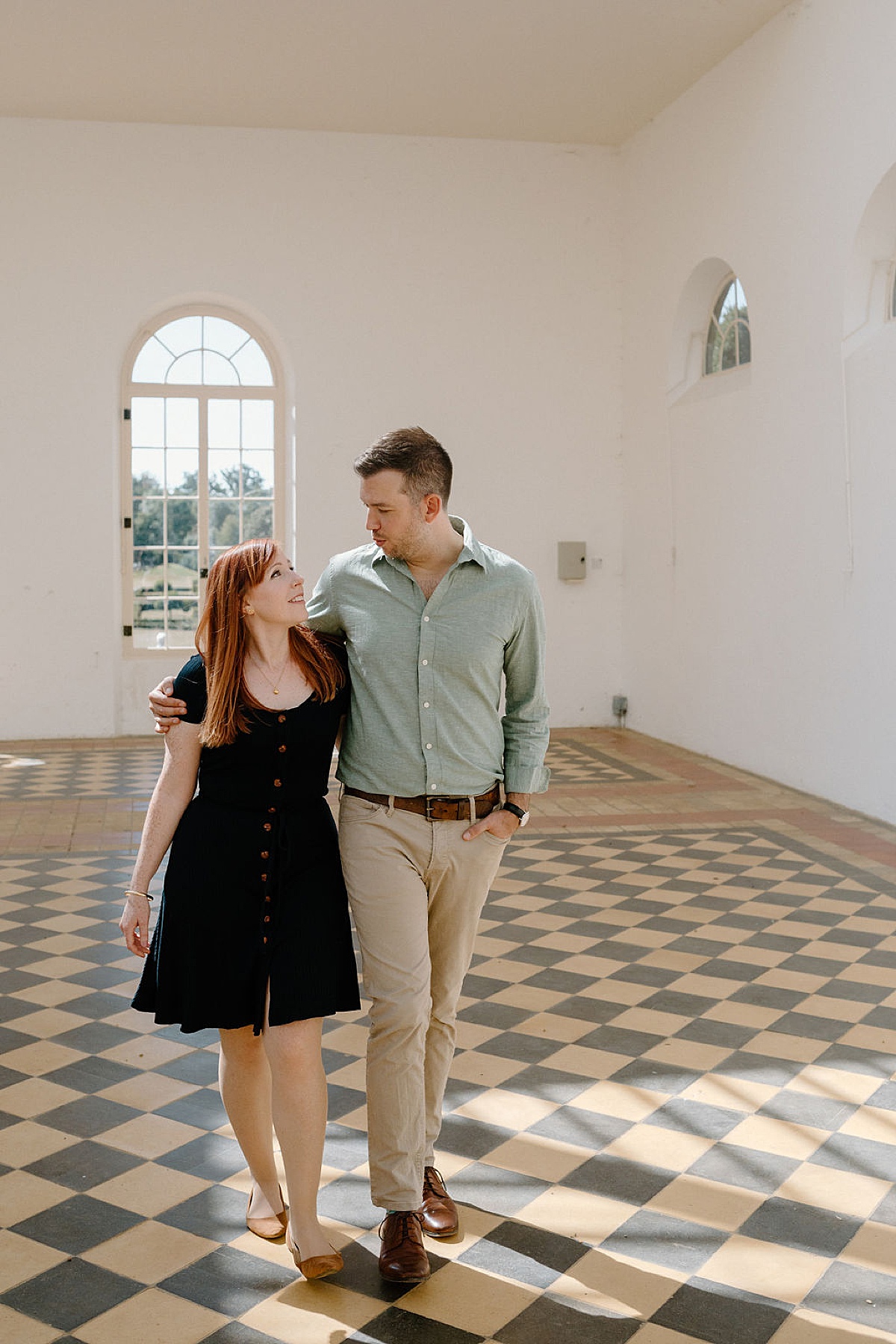 couple walk through garden pavilion with tiled floor during classy engagement shoot by Indigo Lace Collective