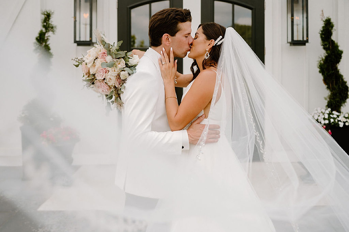 elegant bride and groom kiss in front of modern barn romantic Etre Farms summer wedding