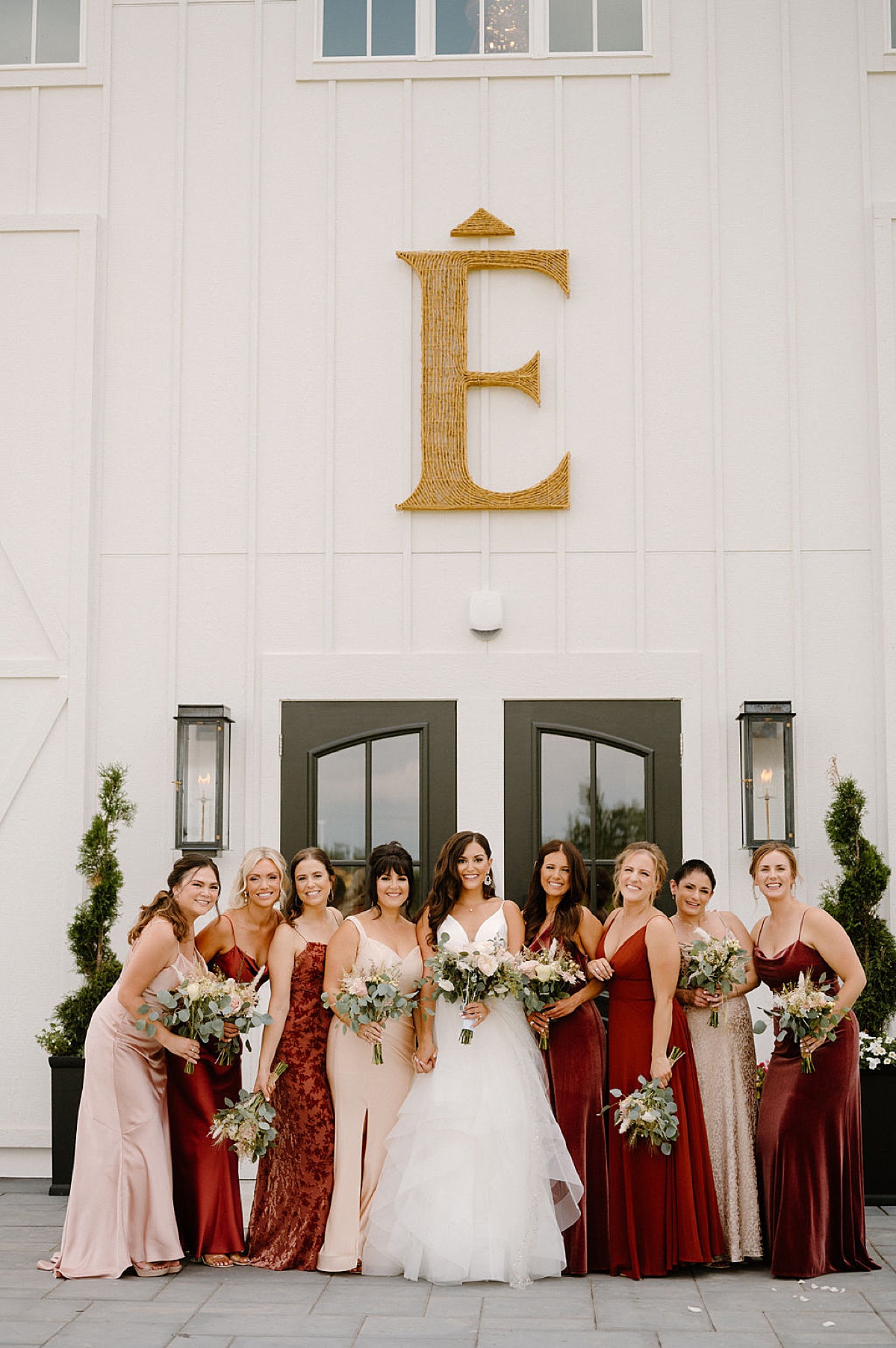 bride in tulle gown poses with bridal party in burgundy and champagne gowns at romantic Etre Farms summer wedding