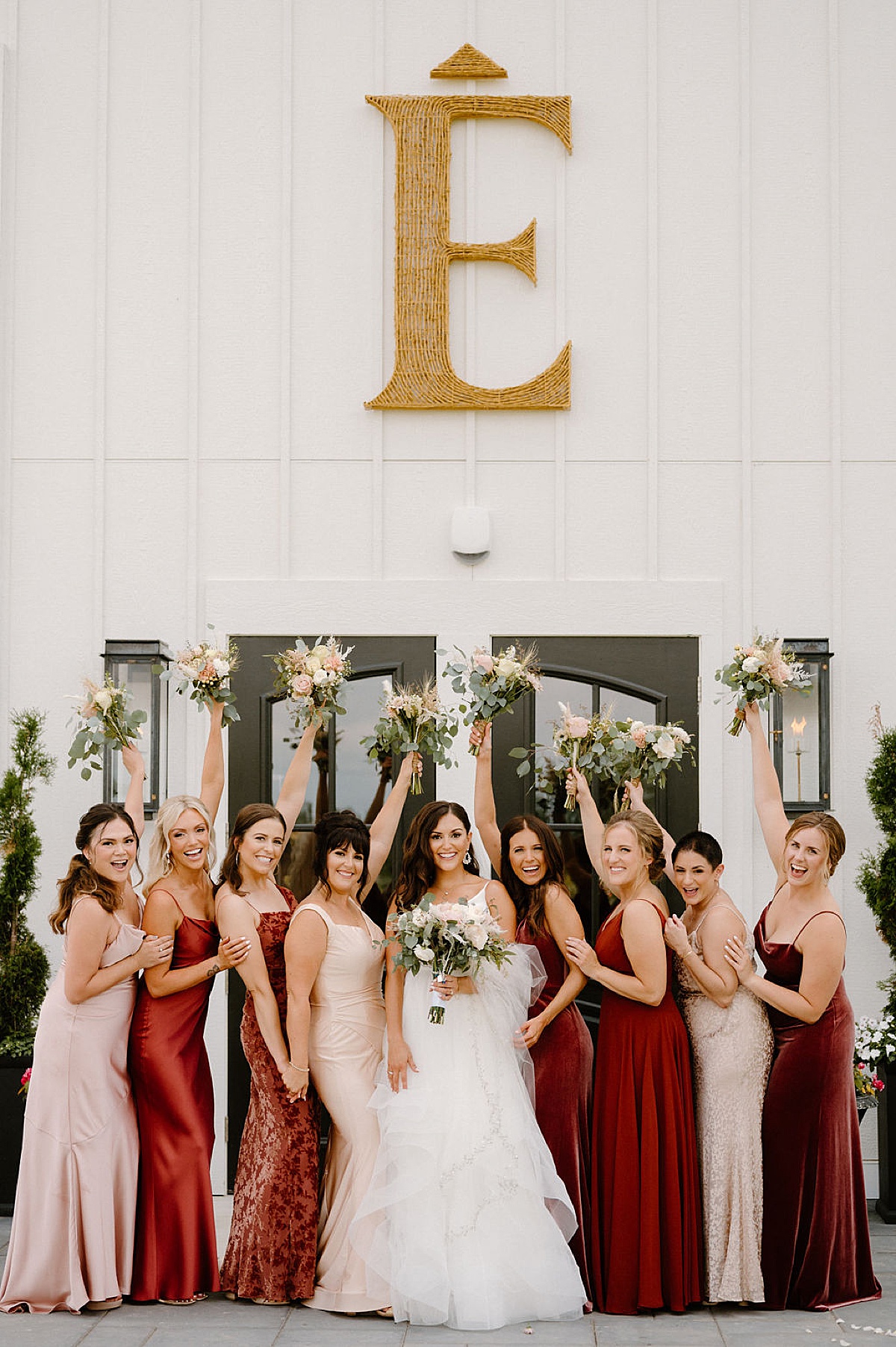 bride in romantic gown poses with bridesmaids in burgundy and champagne pink dresses before wedding shot by Indigo Lace Collective