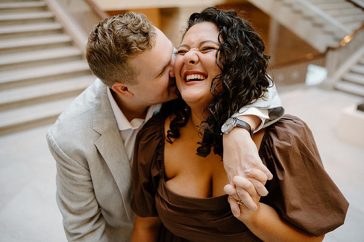 man kisses woman's cheek on steps during Flirty art institute engagement shoot