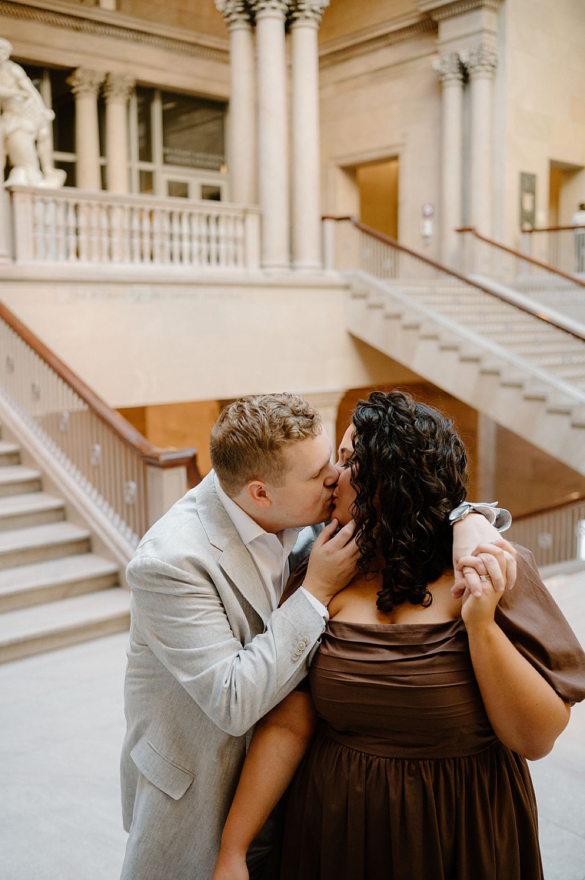 couple kisses on iconic grand staircase during Flirty art institute engagement shoot