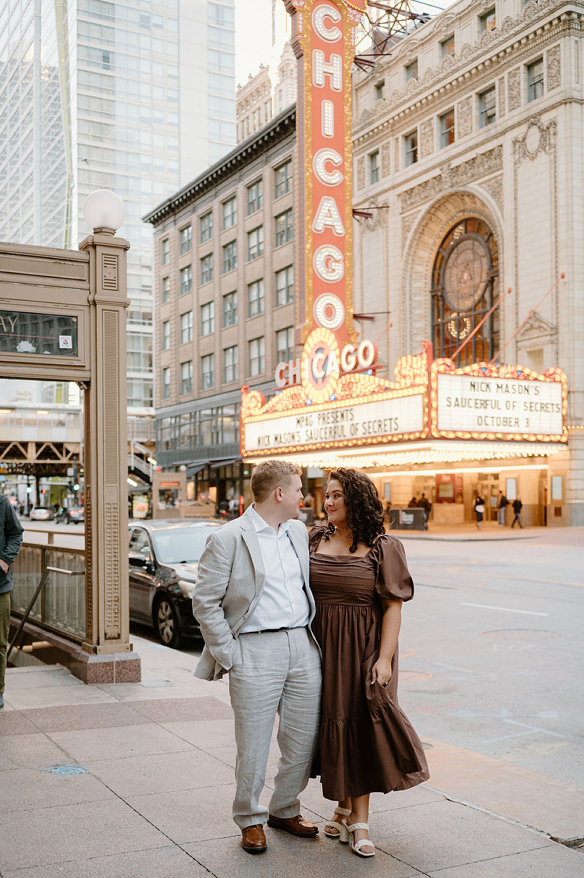 young cute couple pose in front of chicago theatre during arsty engagement shoot with Indigo Lace Collective
