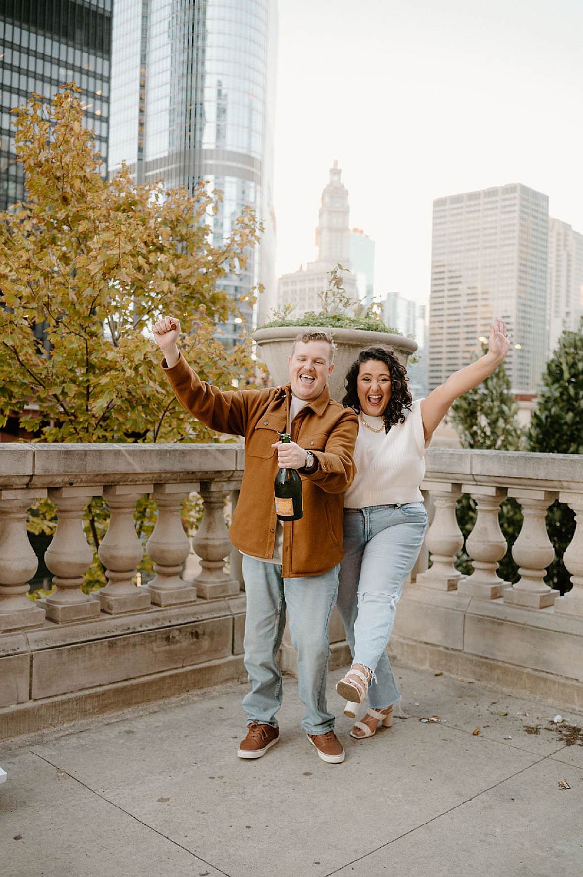 hip couple pops bottle of champagne during fun artsy engagement shoot with Chicago wedding photographer