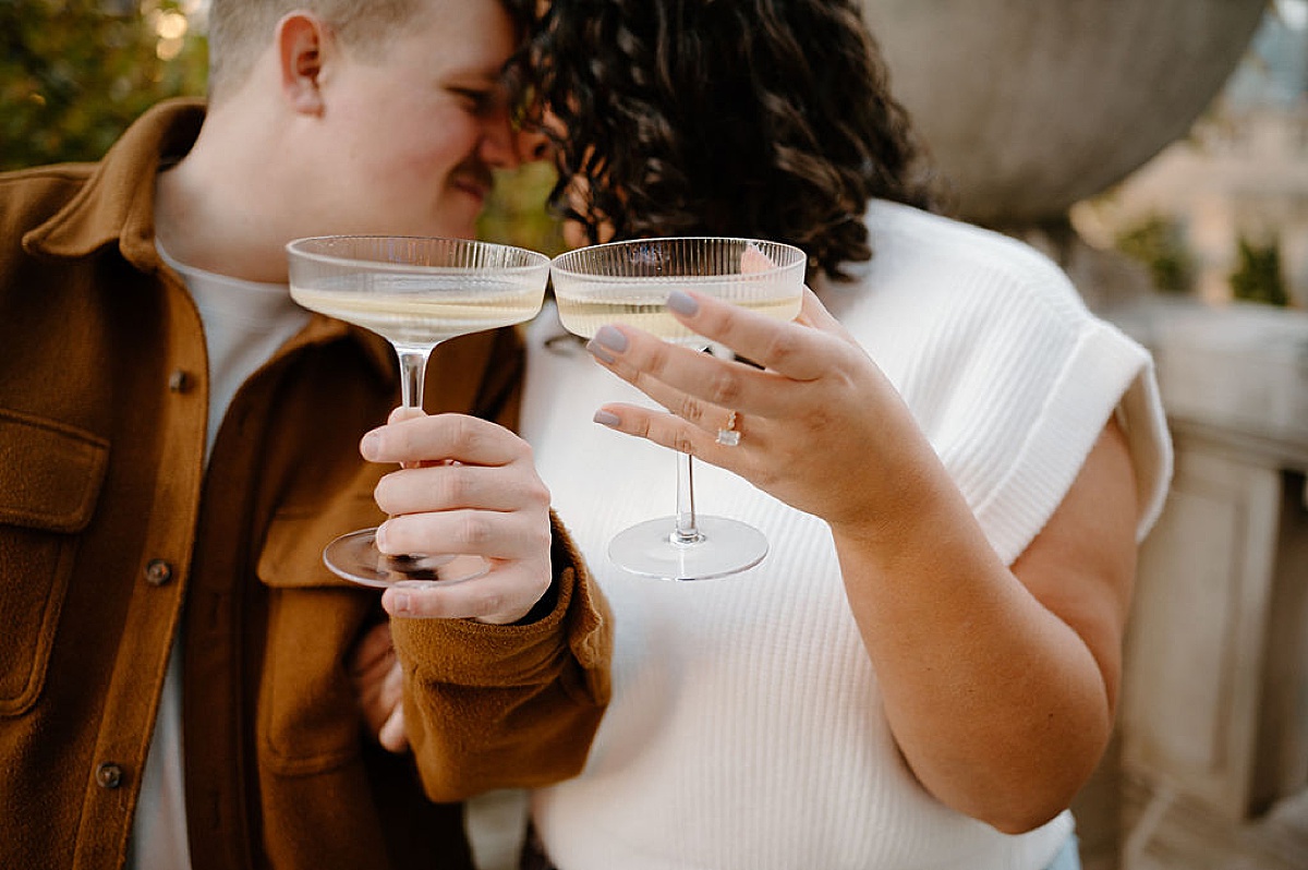 couple cheers glasses of champagne during unique engagement photoshoot with Chicago wedding photographer